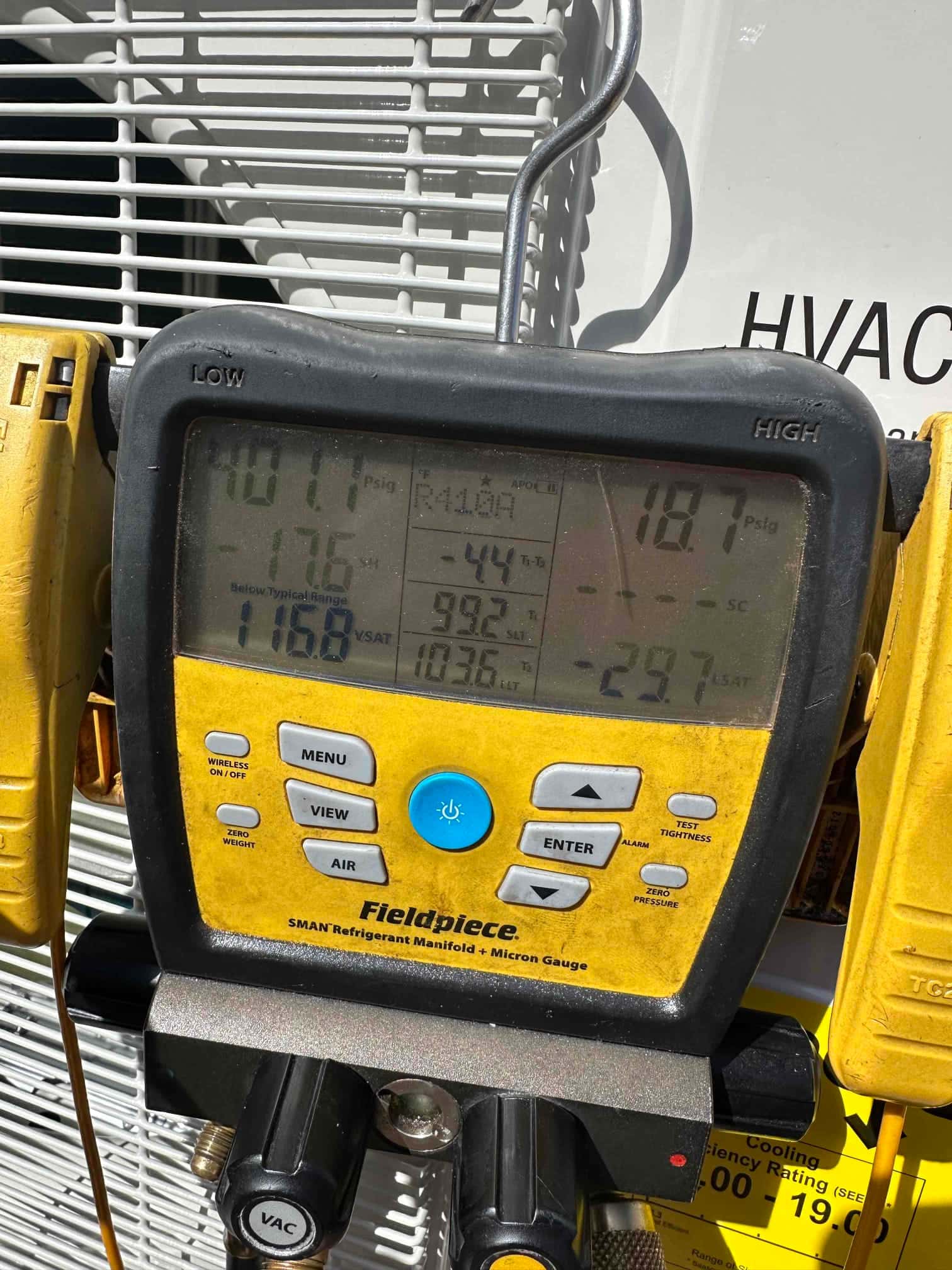 Digital manifold on the outdoor unit shows operating pressures during system commissioning with distinct low and high side readings.