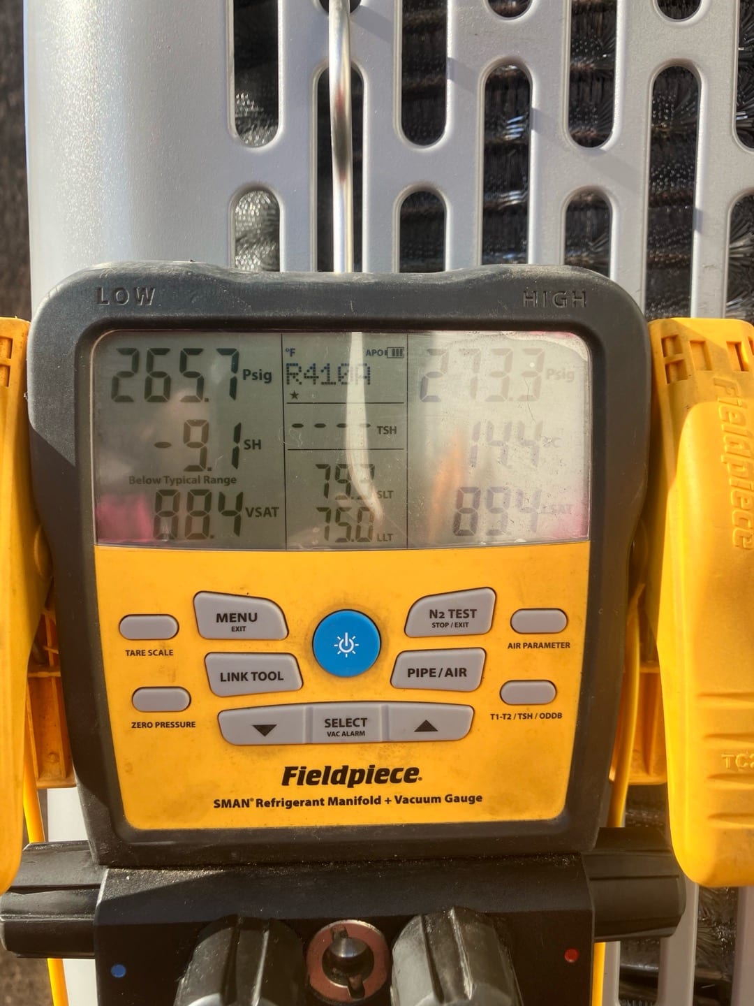 Digital manifold shows operating pressures while commissioning the outdoor unit, documenting live suction and liquid pressures for R-410A.