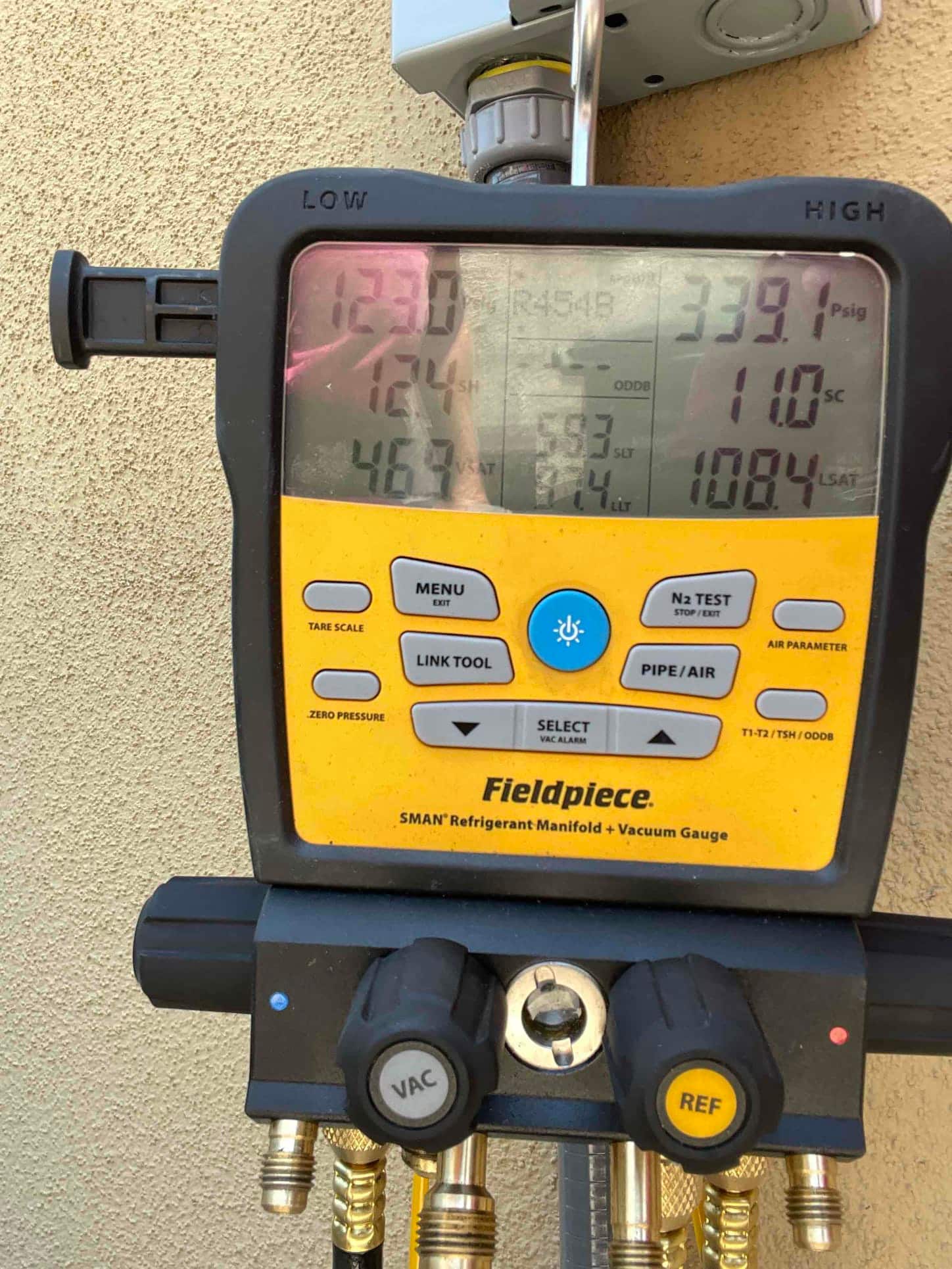 Digital manifold shows operating pressures with low side at 123 PSI and high side at 339 PSI during system commissioning.