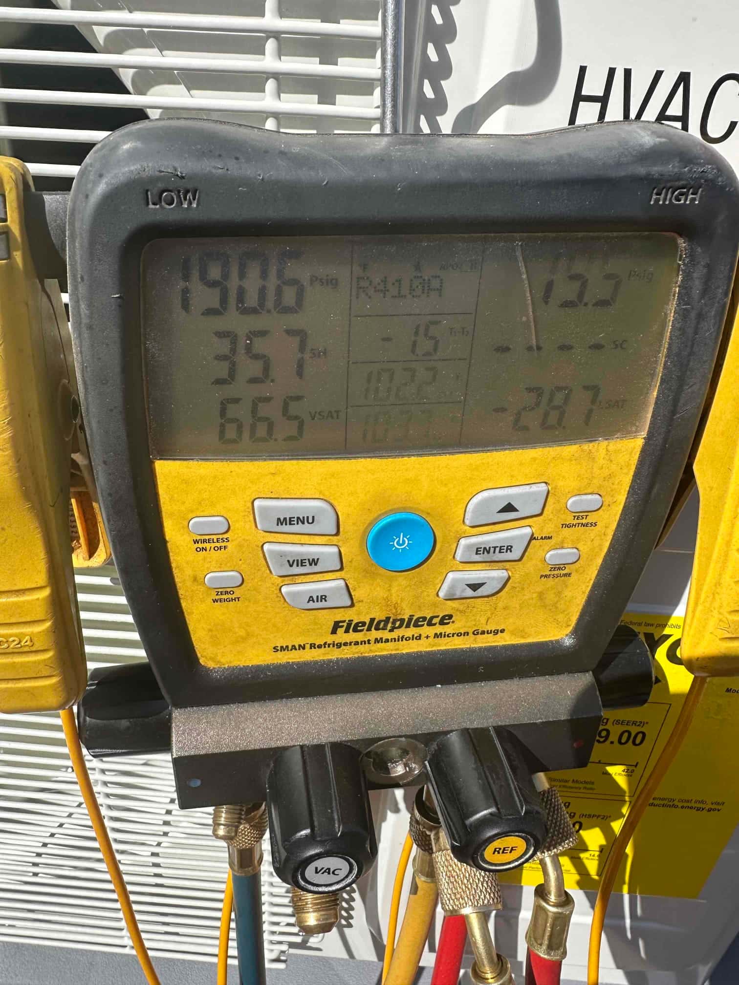 Digital manifold shows operating pressures on a running system, with low and high sides connected during commissioning checks.