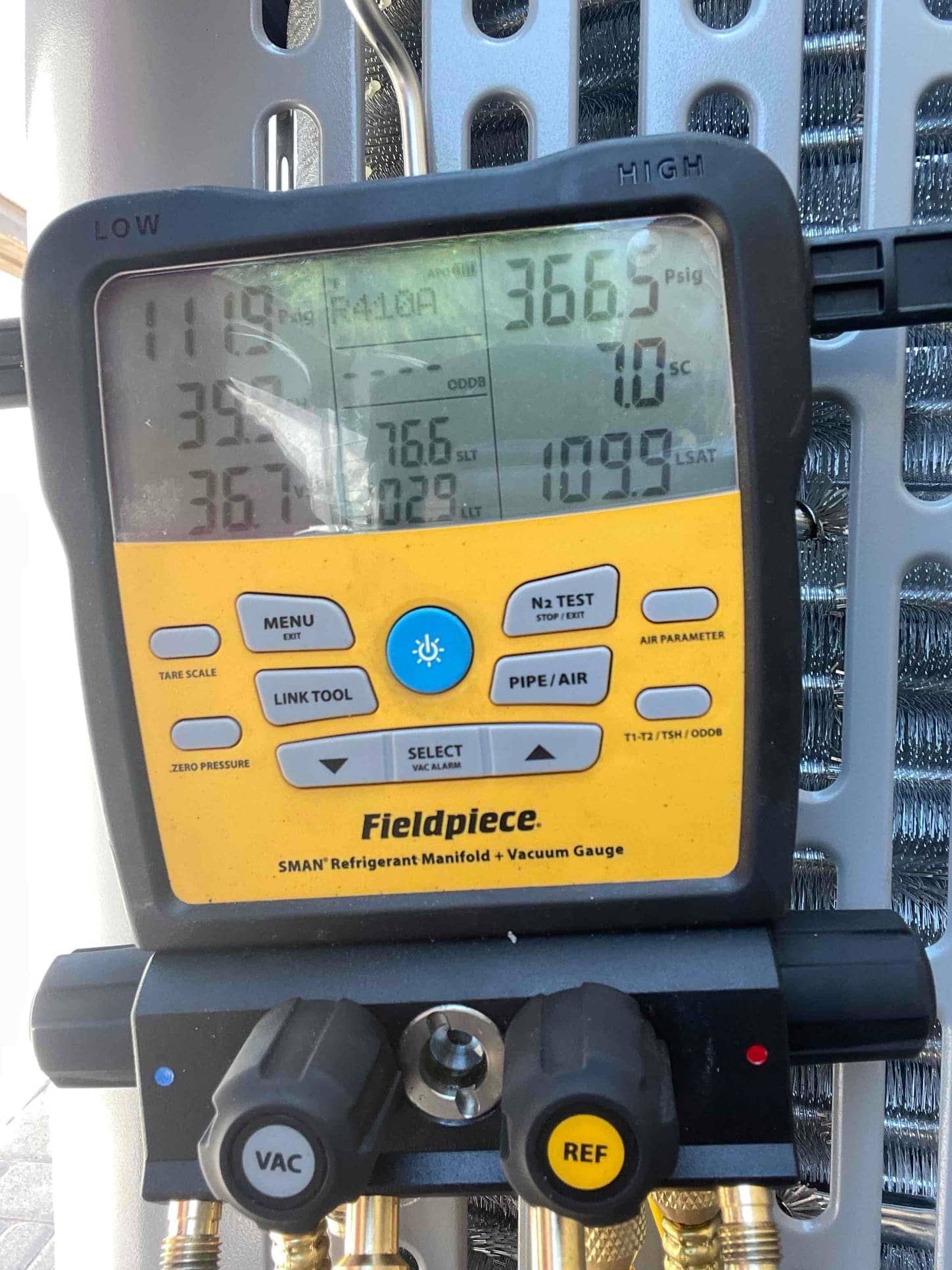 Digital manifold shows system operating pressures with low side at 111 PSI and high side at 366 PSI during commissioning.