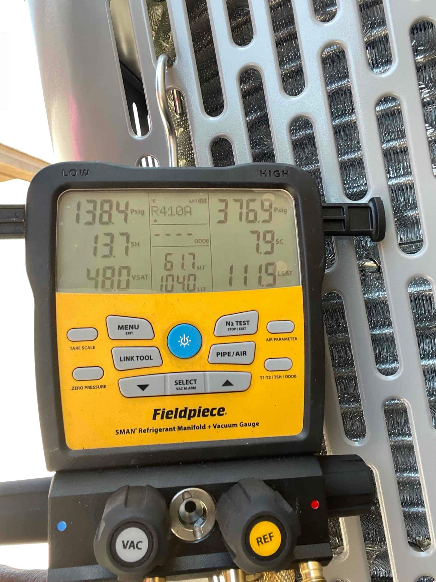 Digital manifold shows system operating pressures with low side at 138 PSIG and high side at 377 PSIG during commissioning.