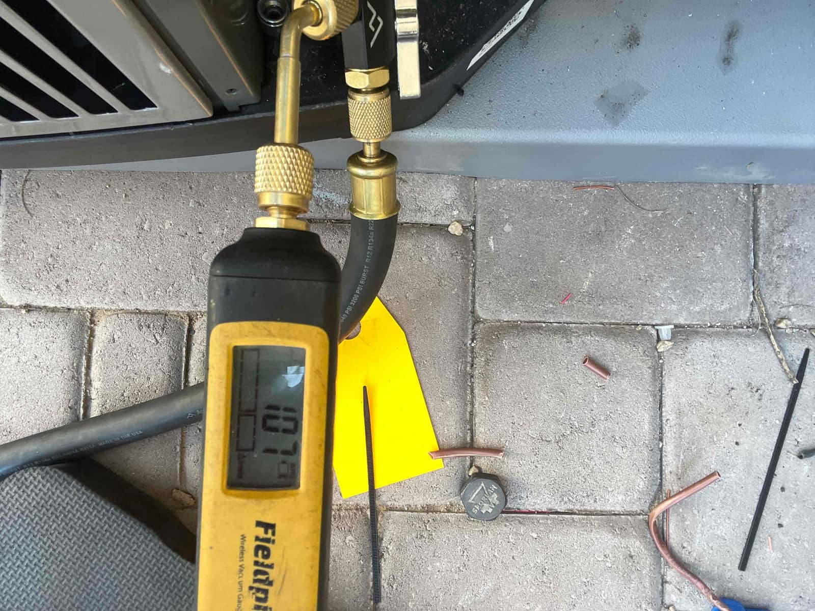 Digital micron gauge connected to the condenser line shows 1070 microns during the evacuation process before refrigerant charging.
