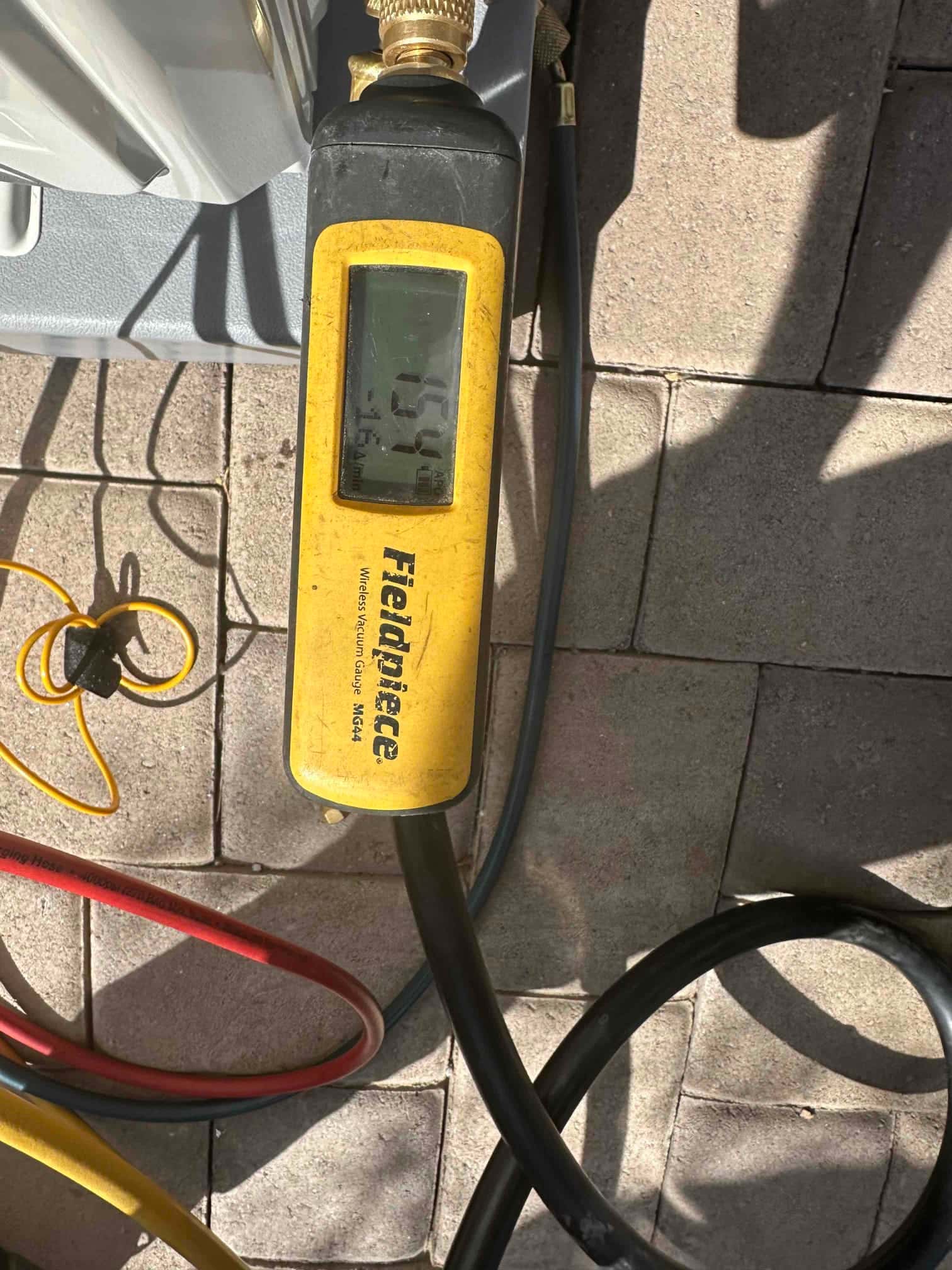 Digital micron gauge connected during evacuation shows a deep vacuum achieved on the new mini‑split installation.