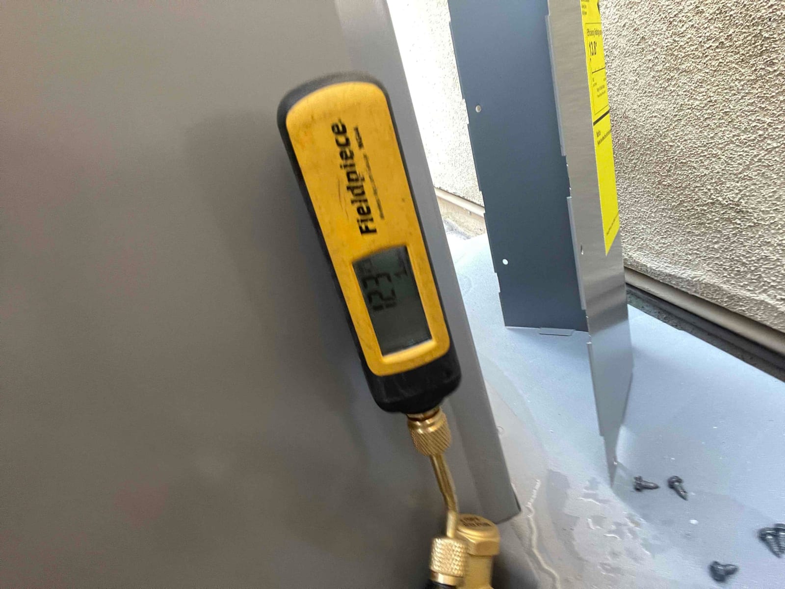 Digital micron gauge connected to the system shows a deep vacuum during evacuation prior to refrigerant charging.