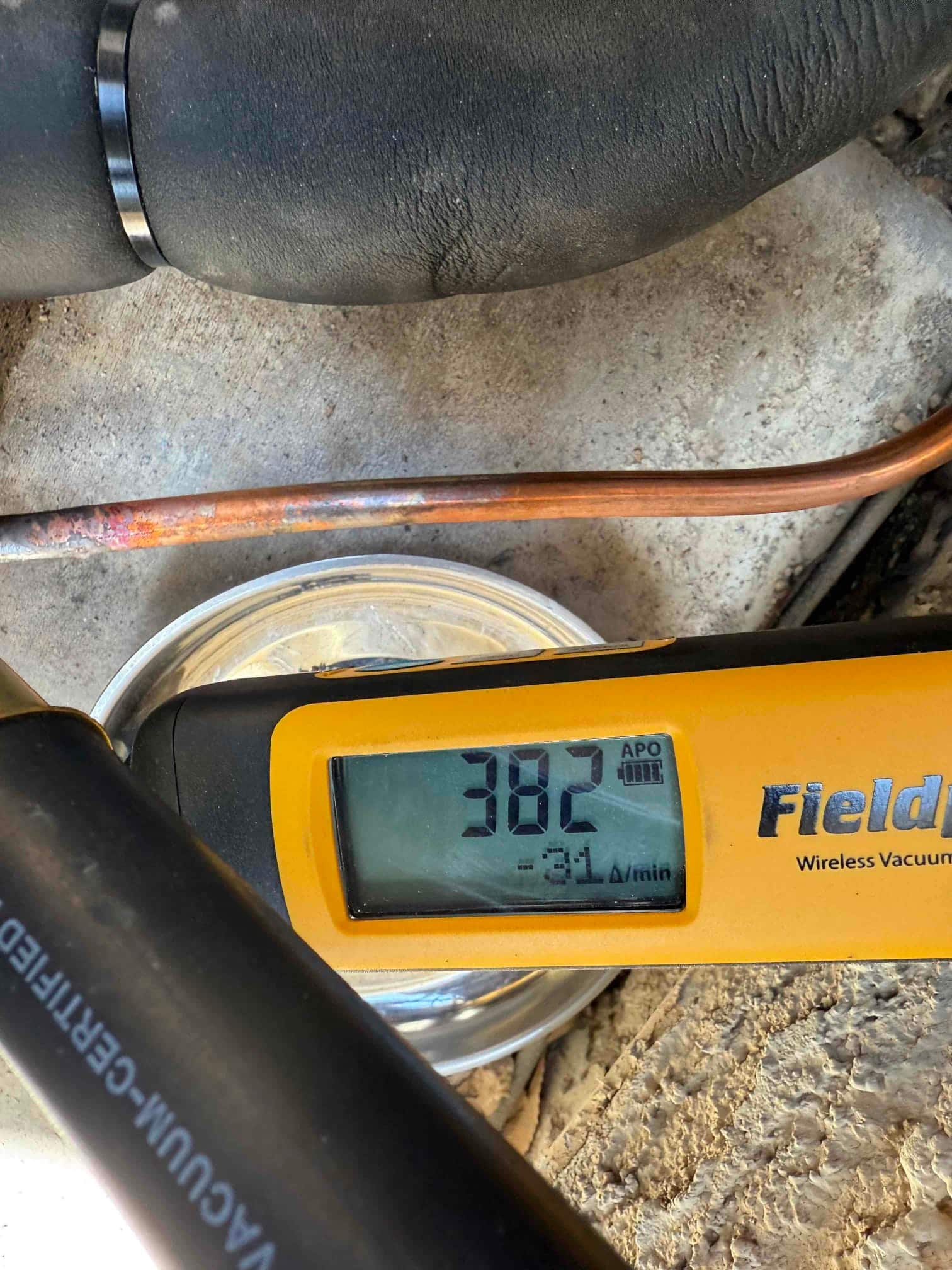 Digital micron gauge on the refrigerant line shows 382 microns, documenting a deep vacuum during system evacuation.