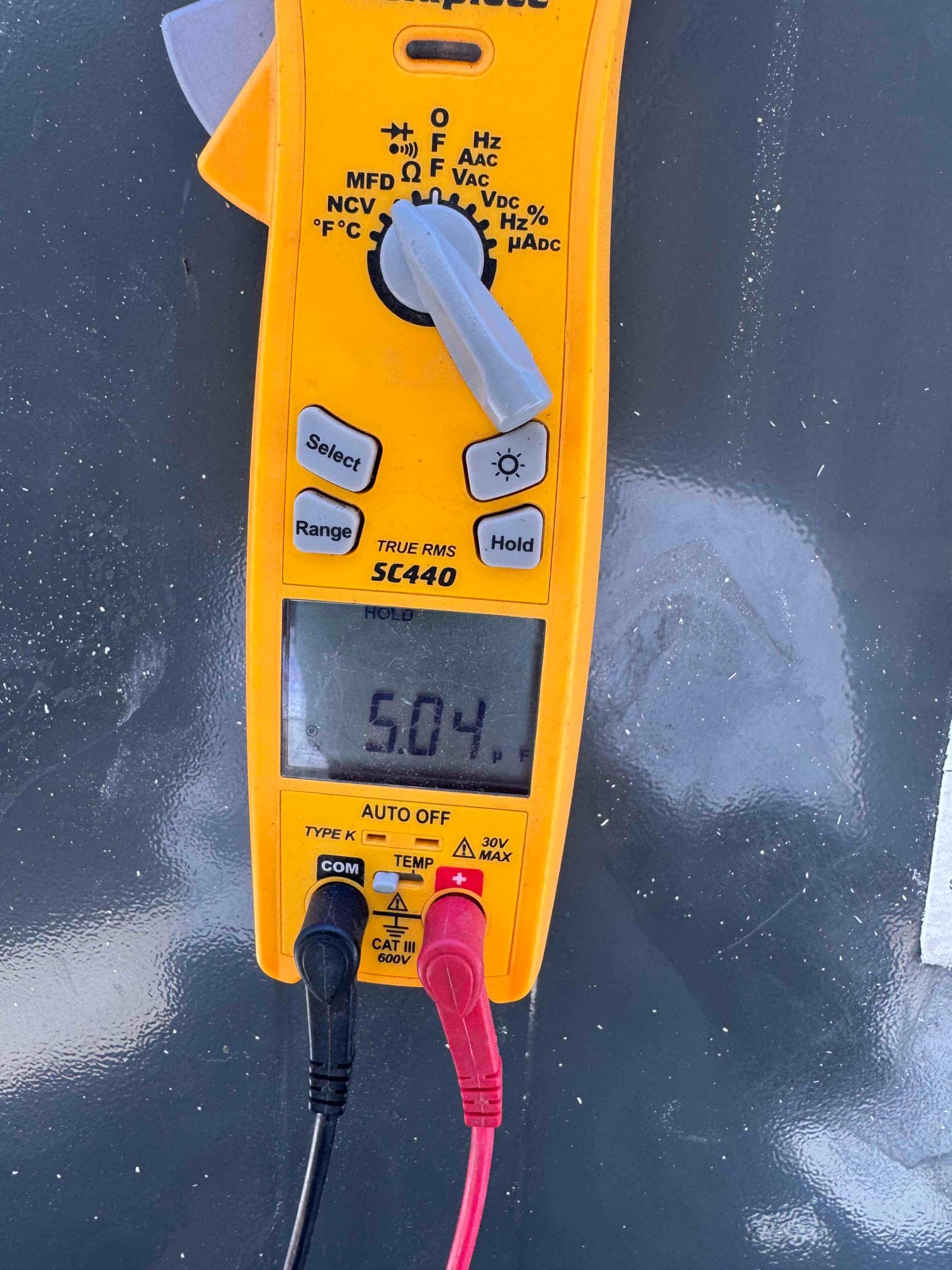 Digital multimeter display shows 5.04 V with test leads connected, documenting a voltage measurement on HVAC equipment.
