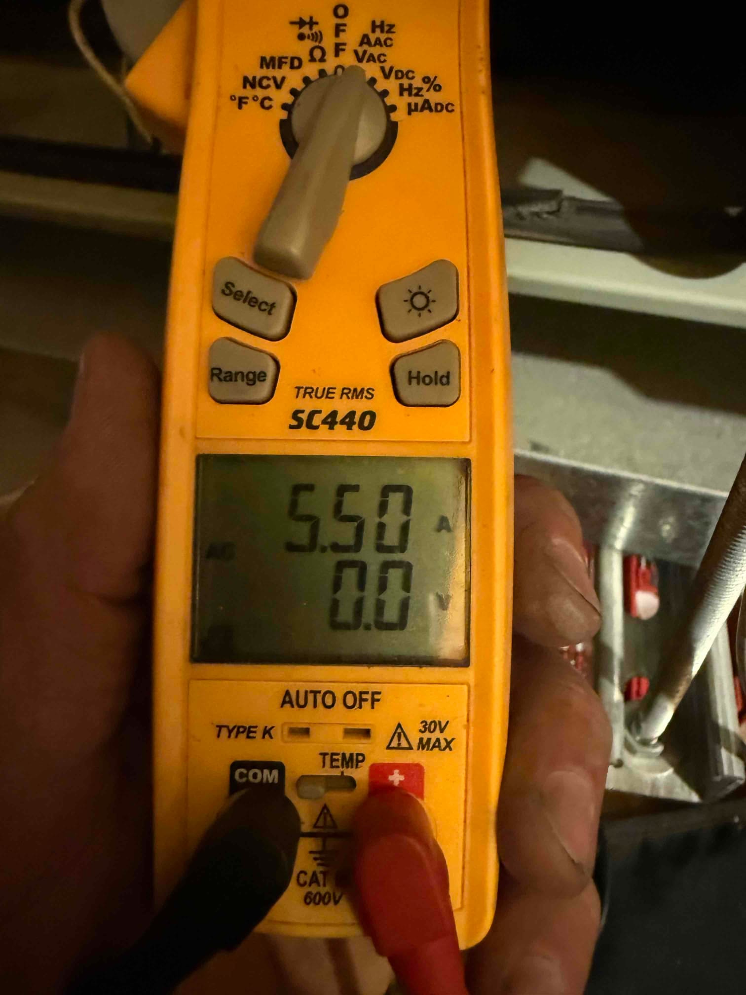Digital multimeter display shows 5.50 A AC with test leads connected, documenting electrical current during HVAC system operation.