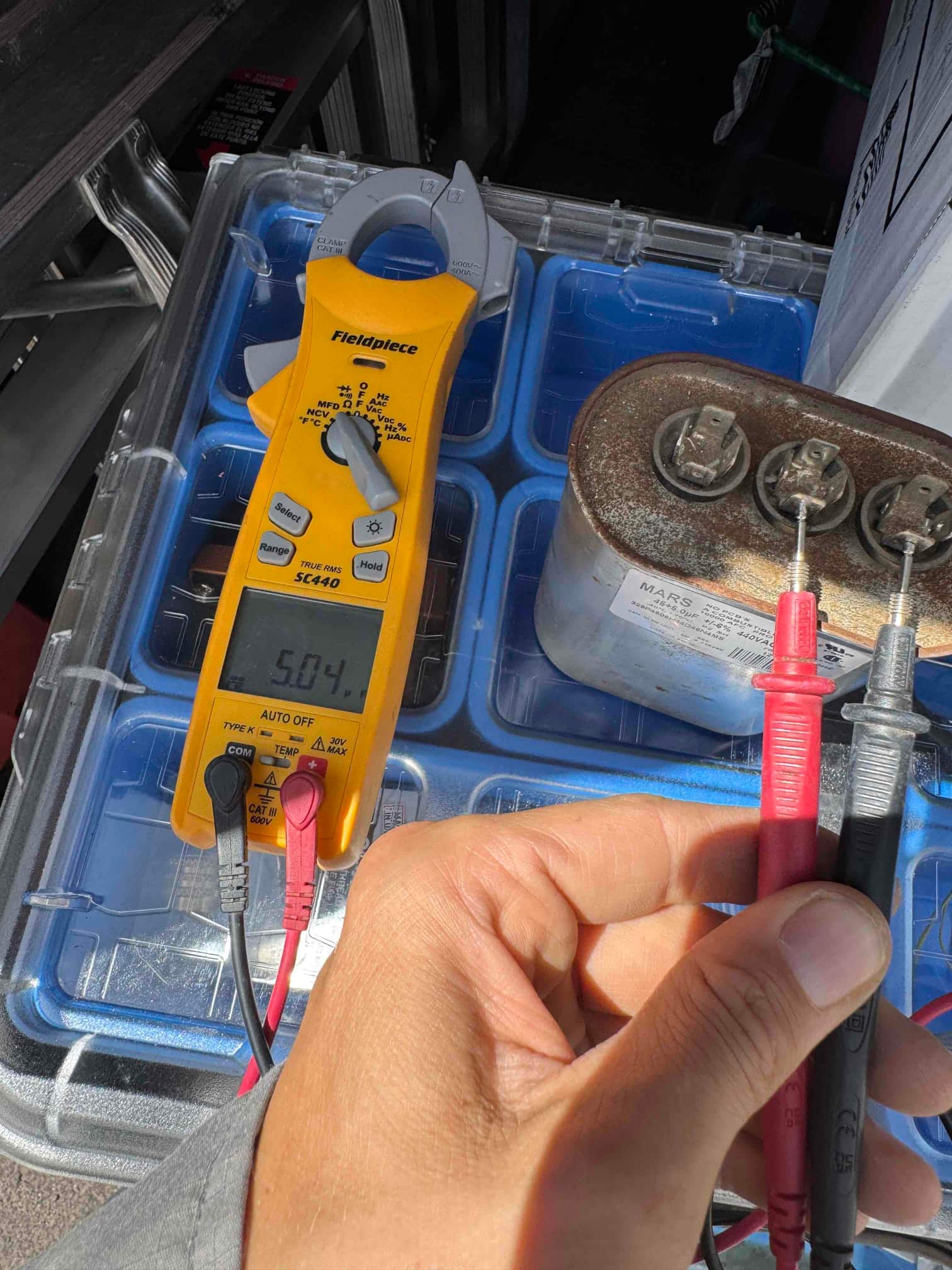 Digital multimeter measures the run capacitor at 50.4 µF with test probes connected to the capacitor terminals.