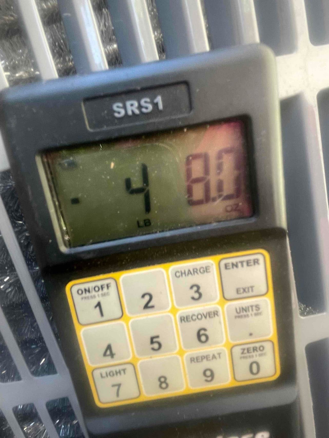 Digital refrigerant scale display shows negative four pounds and 8.0 ounces during charging or recovery at the outdoor unit.