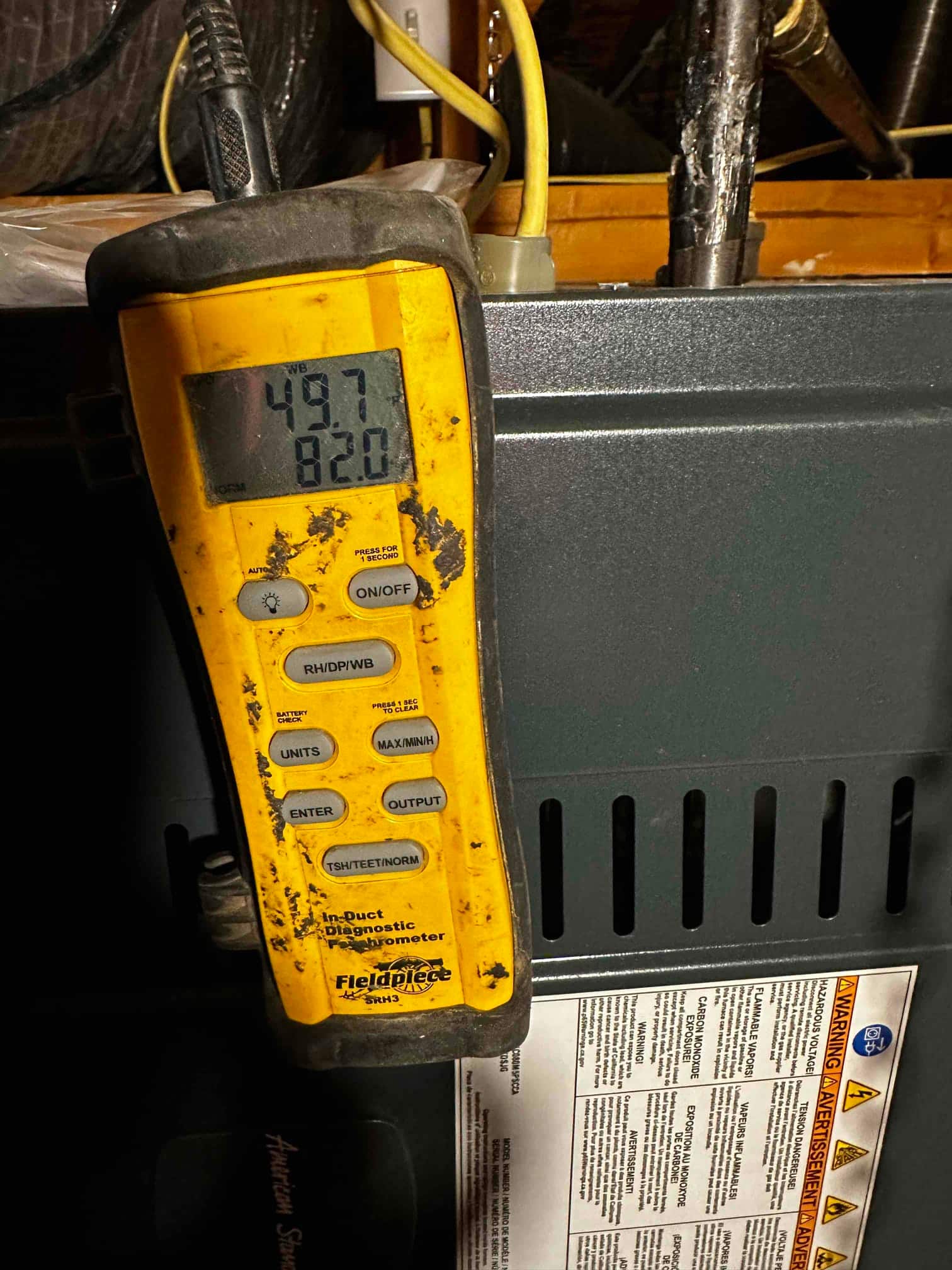 Digital thermometer on the air handler shows 49.7 degrees, documenting cold supply air temperature during commissioning.