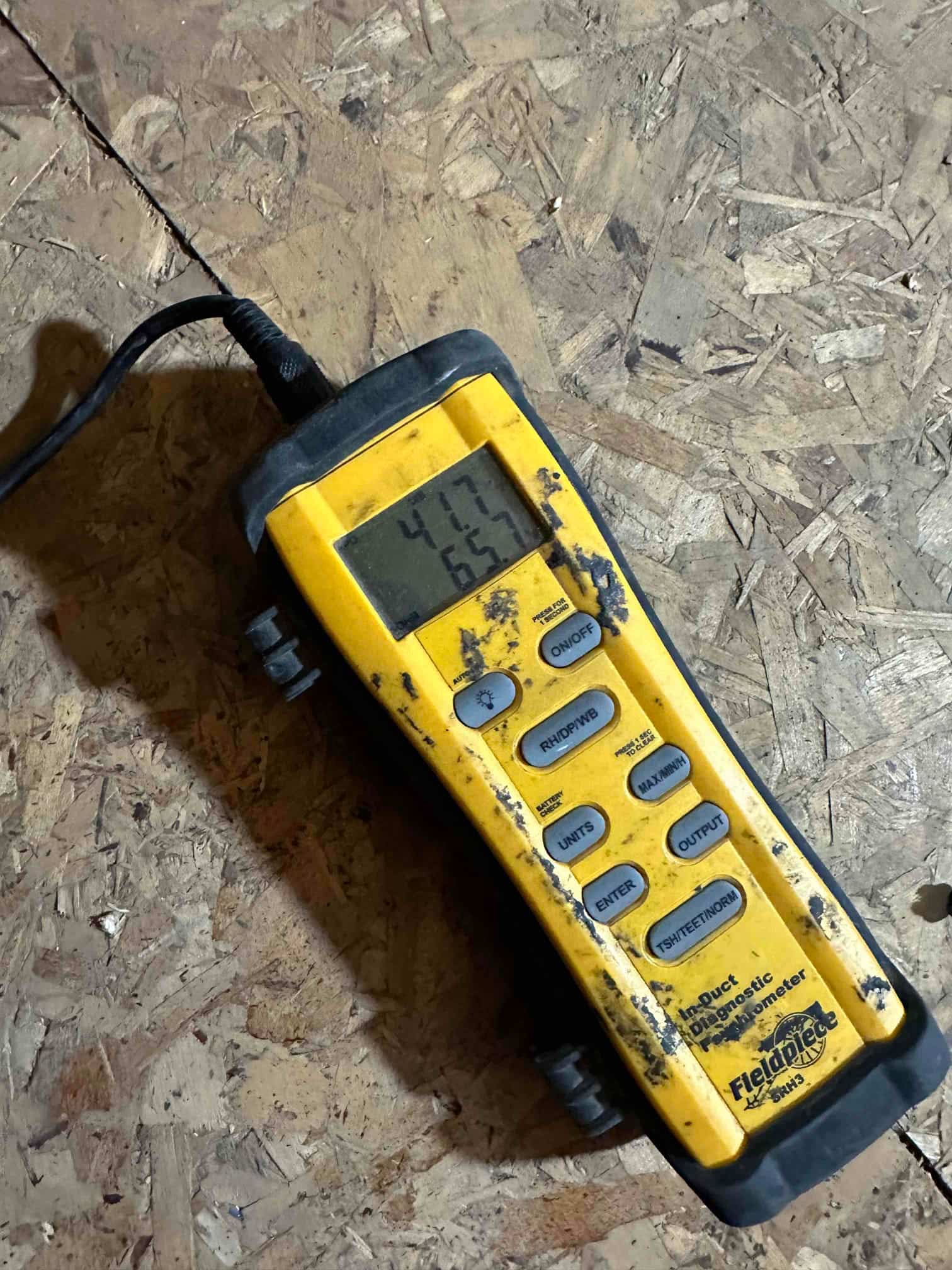 Digital thermometer displays 41.7 and 65.7 degrees while measuring air temperatures during HVAC commissioning.