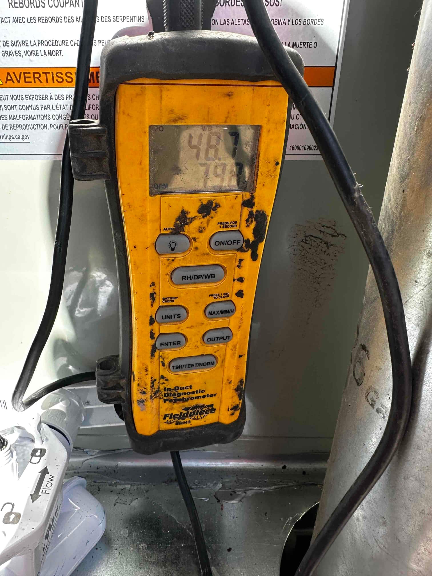 Digital thermometer displays 48.7 degrees in the supply plenum, documenting cooled air temperature after the evaporator.