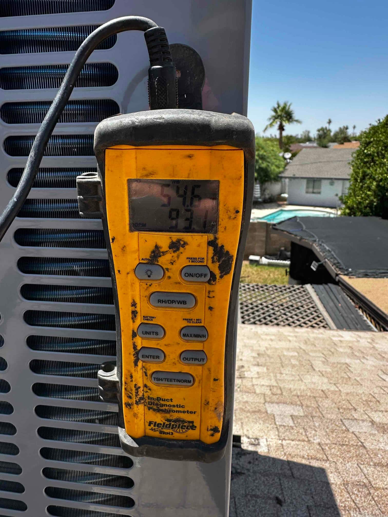 Digital thermometer displays 54.6 degrees Fahrenheit, documenting cold supply air temperature at the outdoor package unit.