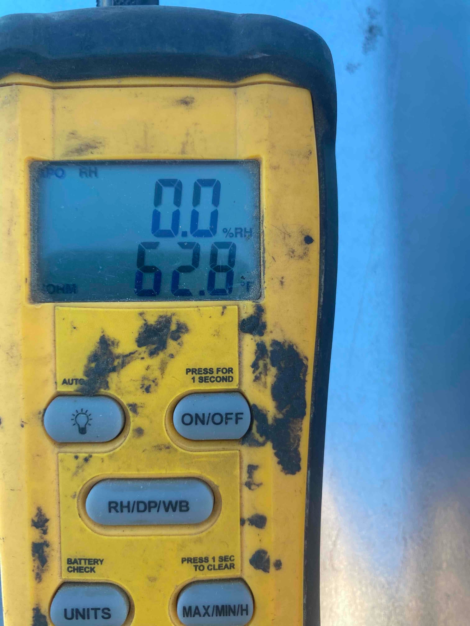 Digital thermometer displays 62.8 degrees Fahrenheit during air temperature check at the HVAC installation site.