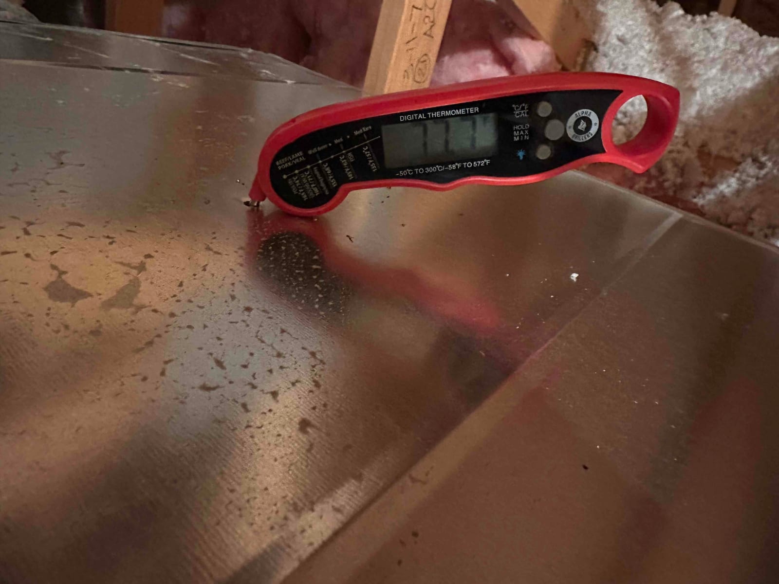 Digital thermometer inserted into ductwork during commissioning to measure air temperature leaving the evaporator.