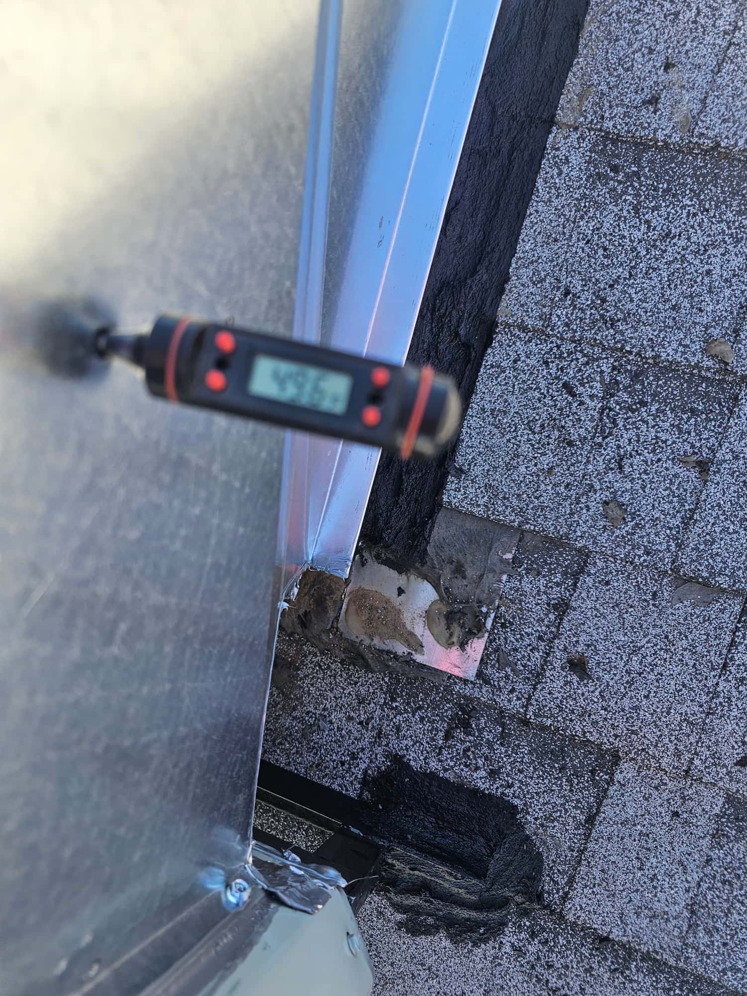 Digital thermometer inserted at the metal duct reads 49.5°F, documenting cool supply air leaving the evaporator.