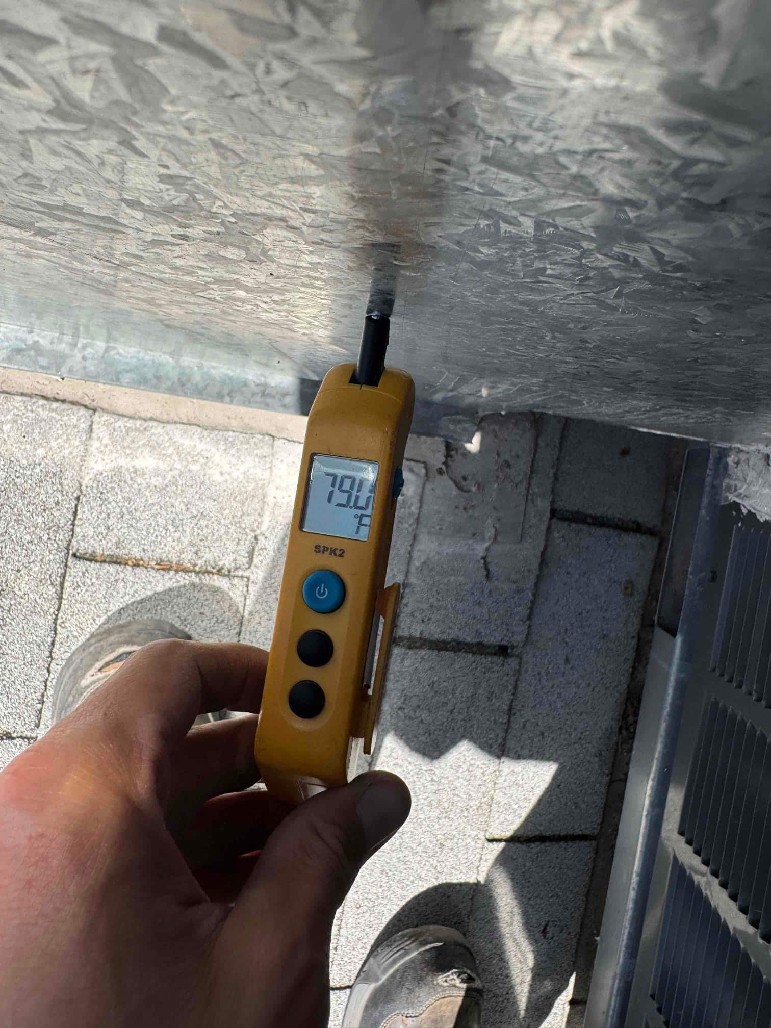 Digital thermometer measures 79.6 °F on a metal surface near the HVAC unit, probe inserted against the panel.