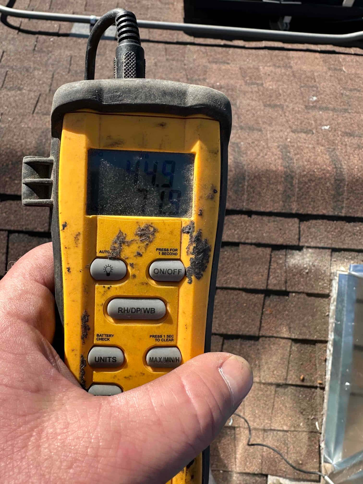 Digital thermometer probe used during commissioning with the display showing an air temperature reading on the rooftop.