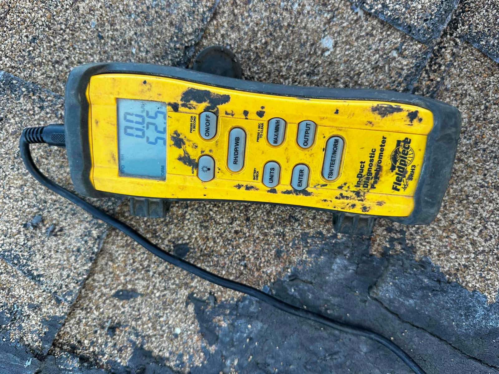 Digital thermometer shows 52.5 degrees Fahrenheit on the display while measuring air temperature during commissioning.