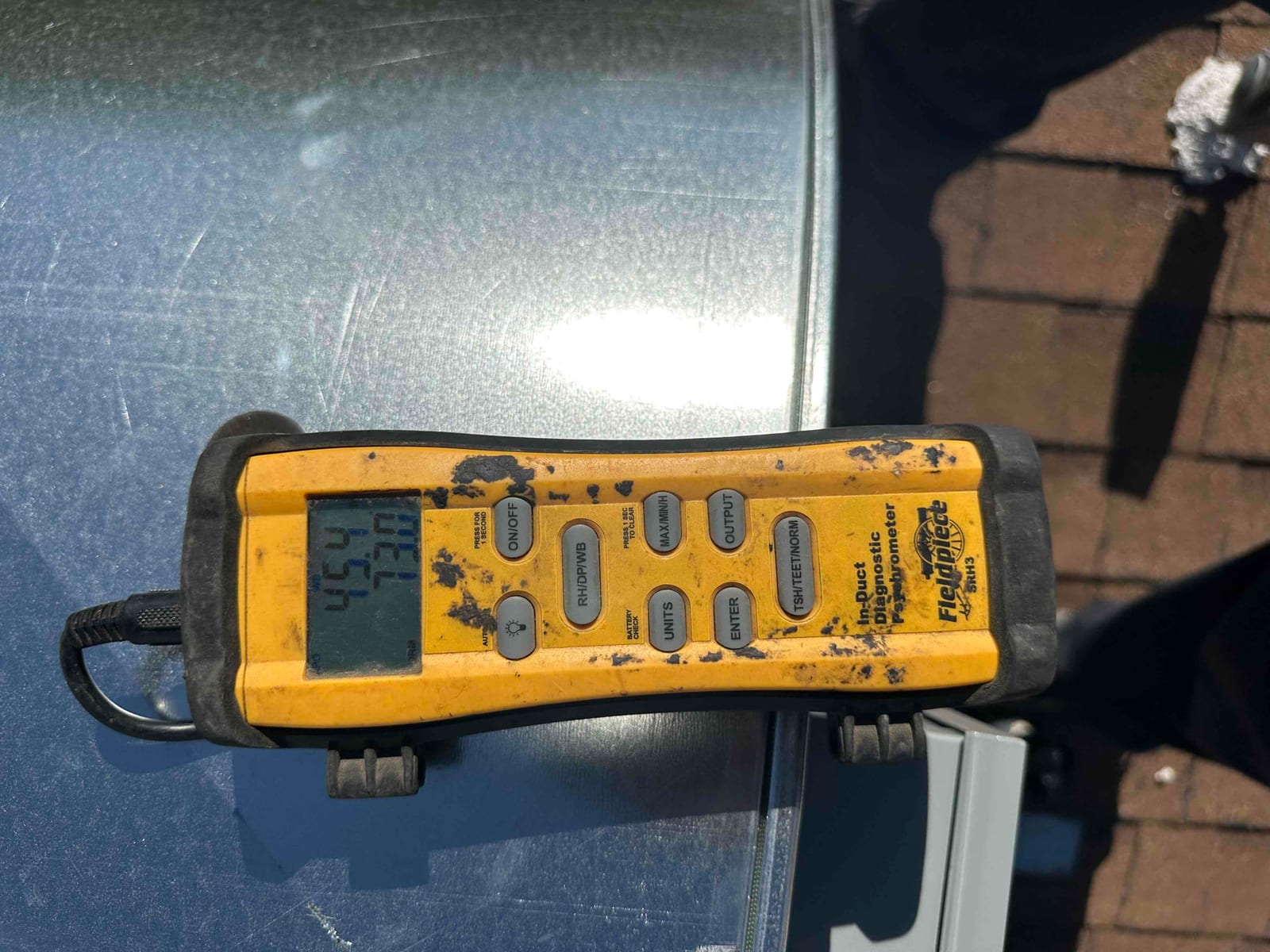 Digital thermometer shows a 73.1°F air reading during commissioning checks at the outdoor unit.
