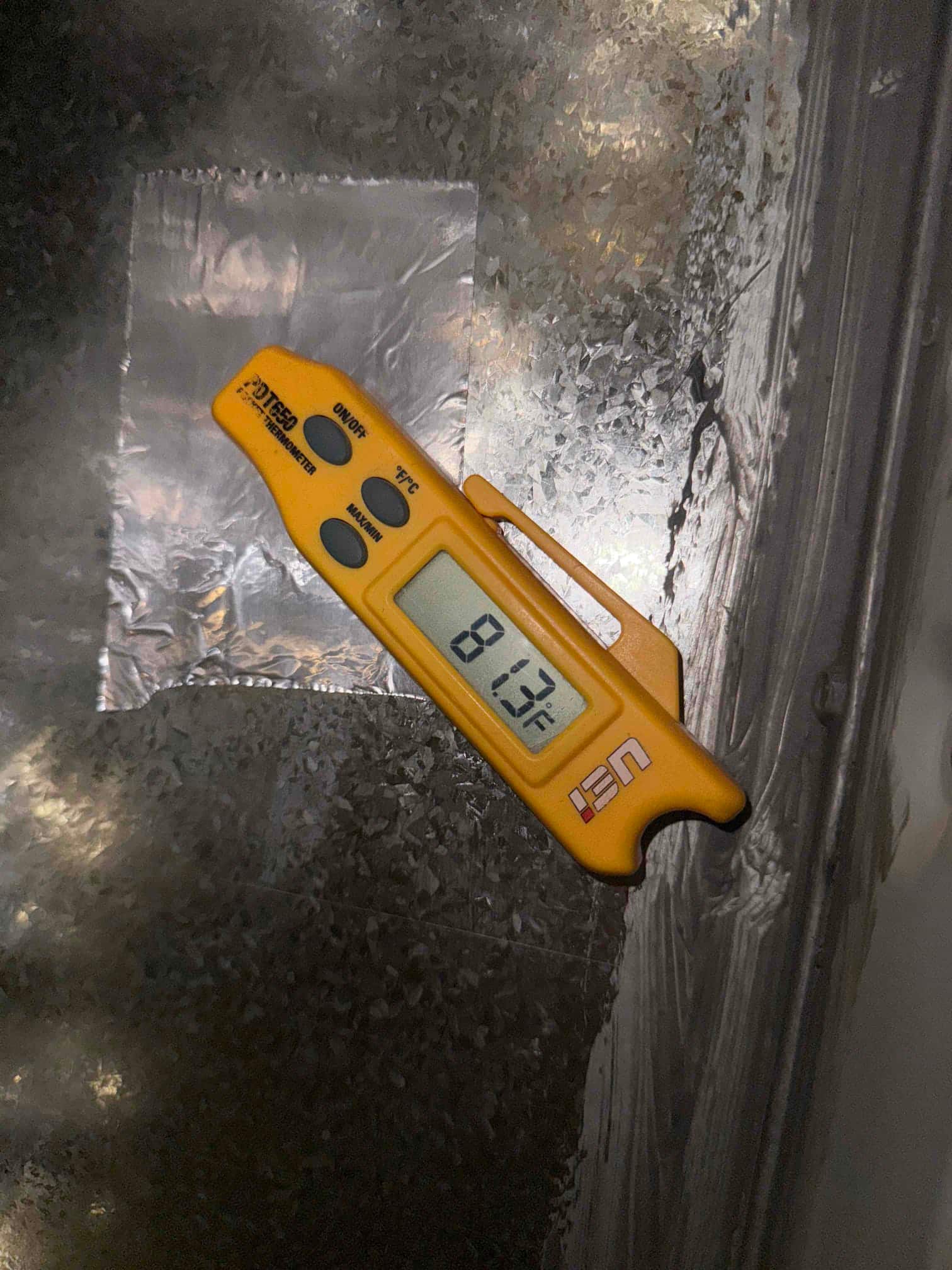 Digital thermometer shows 81.3 °F surface temperature on the metal HVAC panel near the indoor blower section.