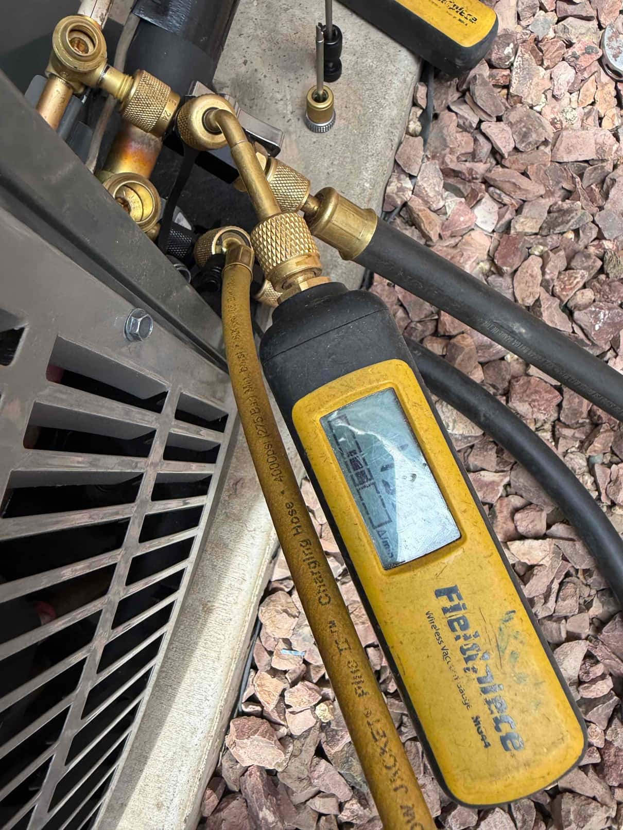 Digital vacuum gauge connected at the outdoor unit shows a deep vacuum during system evacuation prior to refrigerant charging.