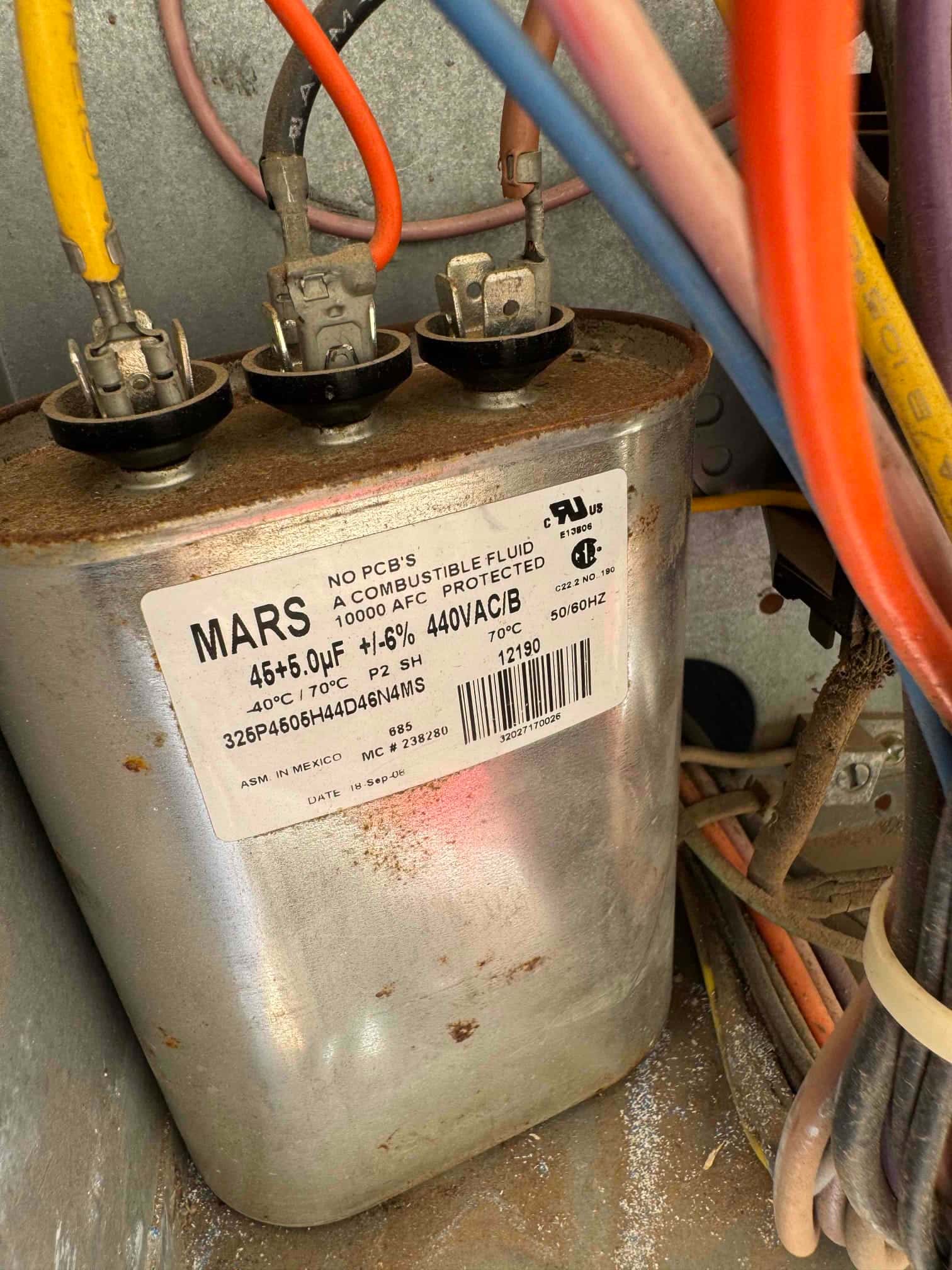 Dual-run capacitor inside condenser cabinet, labeled 45/6+0 μF ±5% 440 VAC, with connected compressor and fan terminals and wiring.
