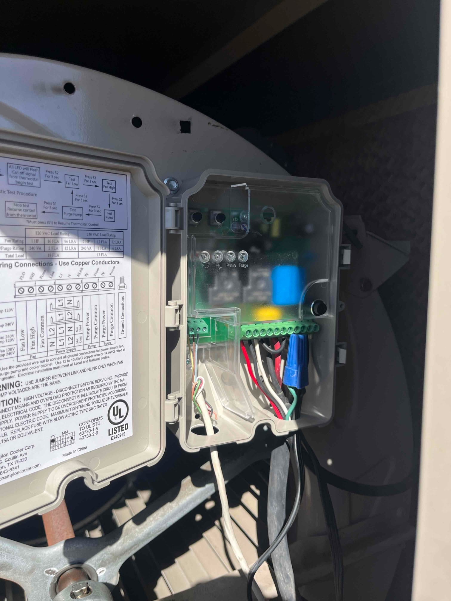 Evaporative cooler control box open, showing wiring, terminal board, blue capacitor, and wiring diagram on the inside cover.