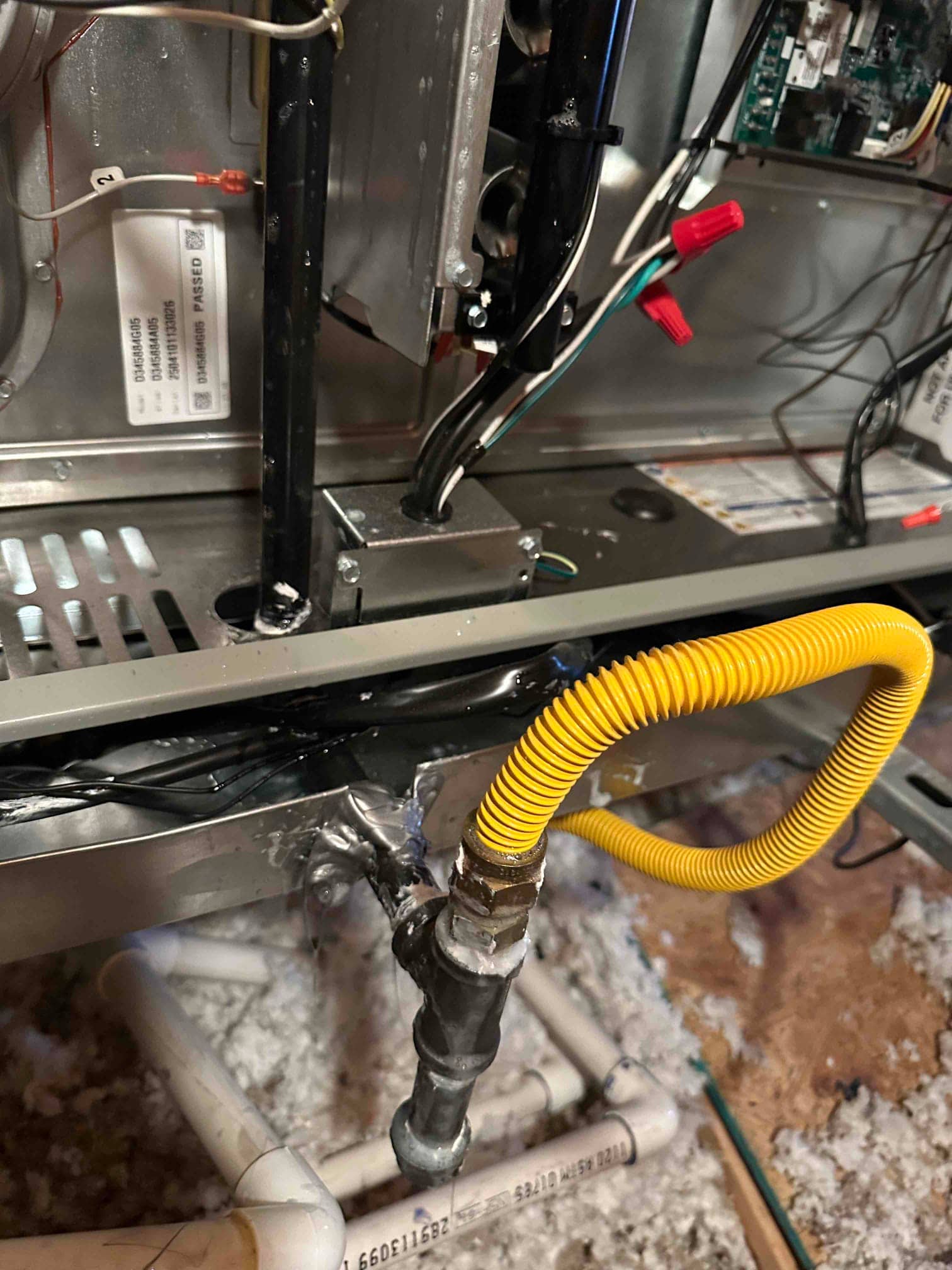 Furnace interior with gas flex connector tied into black iron piping and sealed cabinet penetration, wiring routed through a junction box.
