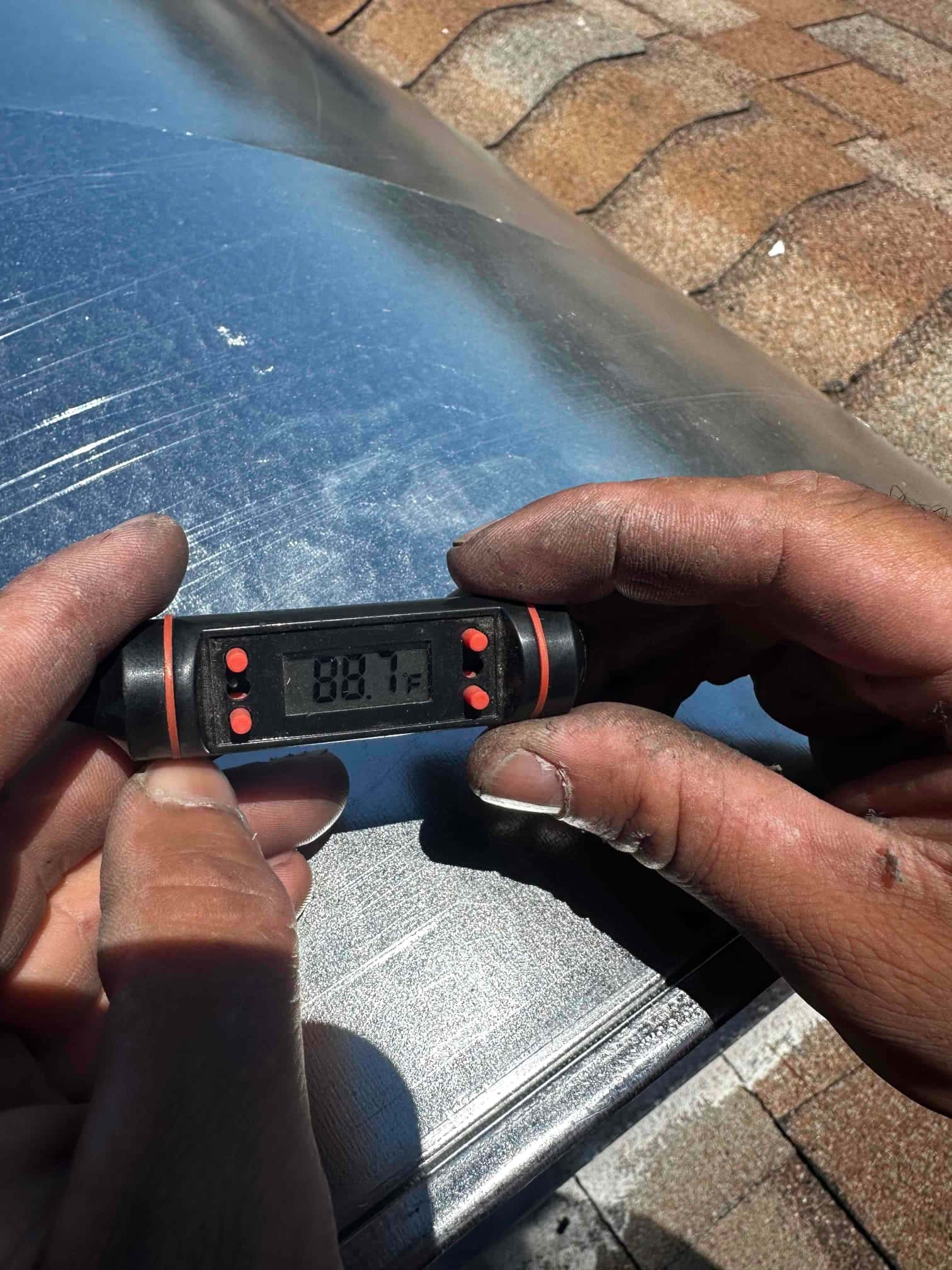 Handheld digital thermometer shows 88.7°F while measuring air temperature during HVAC installation checks.