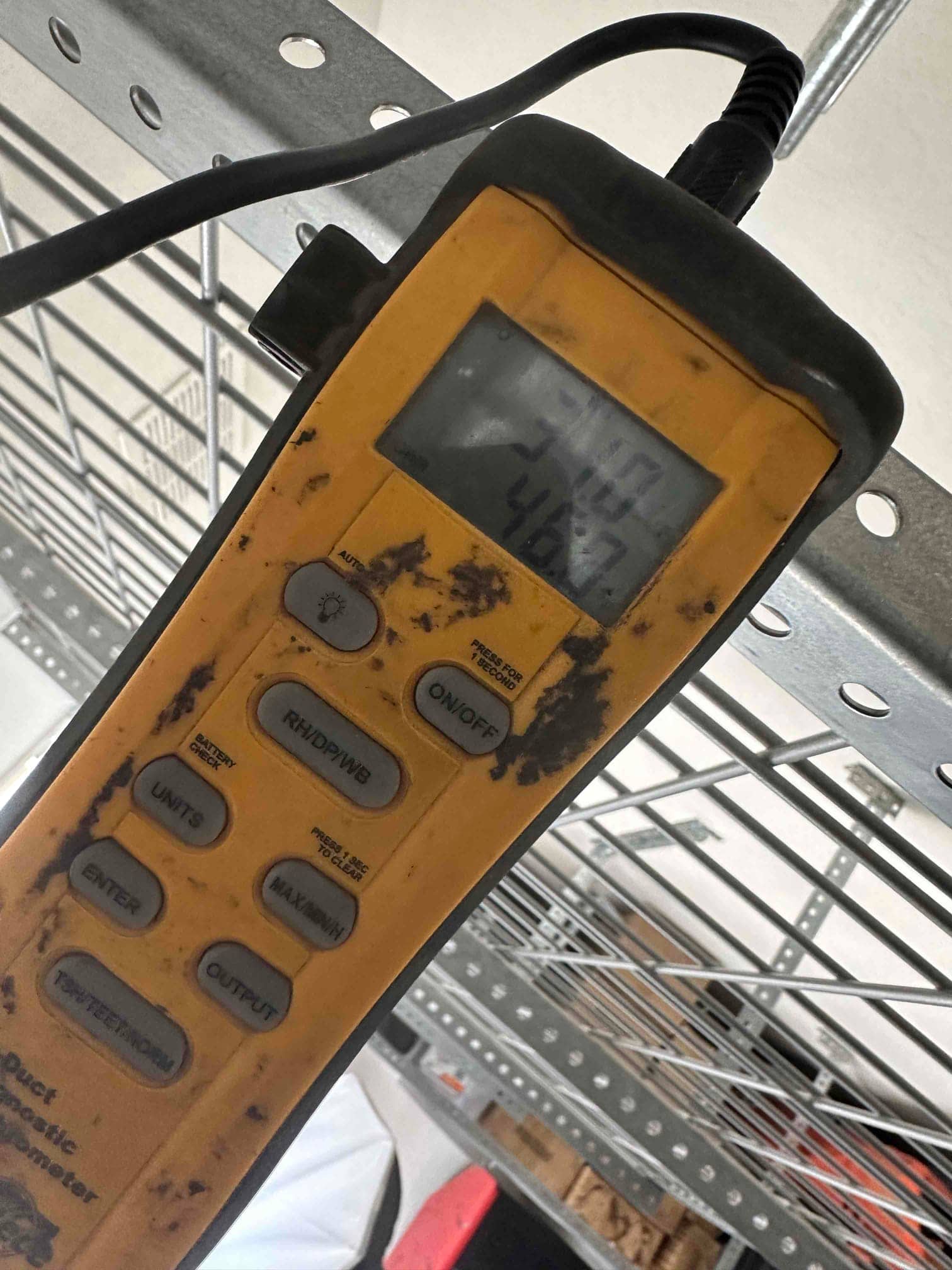 Handheld thermometer/anemometer displays air temperature during commissioning checks of the new mini-split installation.