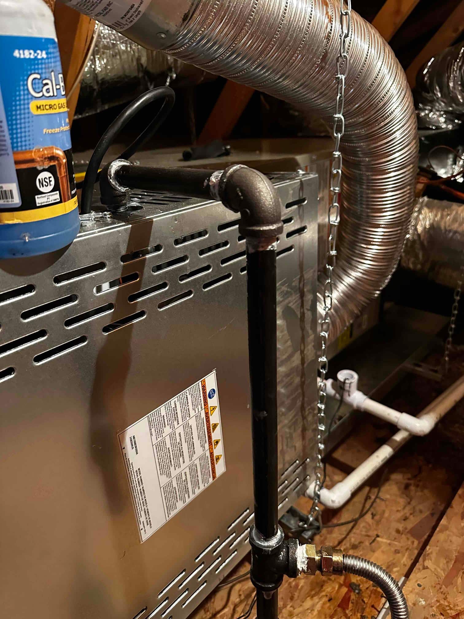 Horizontal furnace installed in attic with gas piping, flexible duct connection, and condensate drain piping secured and supported.