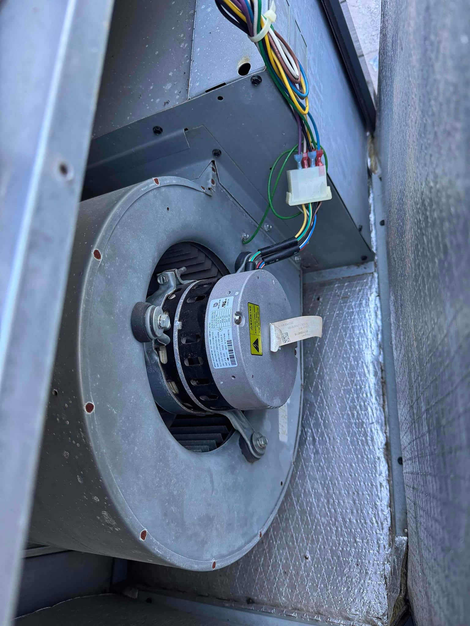 Indoor blower assembly with newly installed blower motor and wiring harness visible inside the air handler housing.