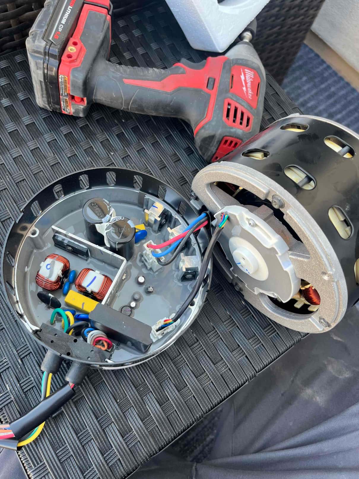 Indoor blower motor removed, showing open ECM control module with wiring, capacitors, and coils during replacement by technician Garrett.