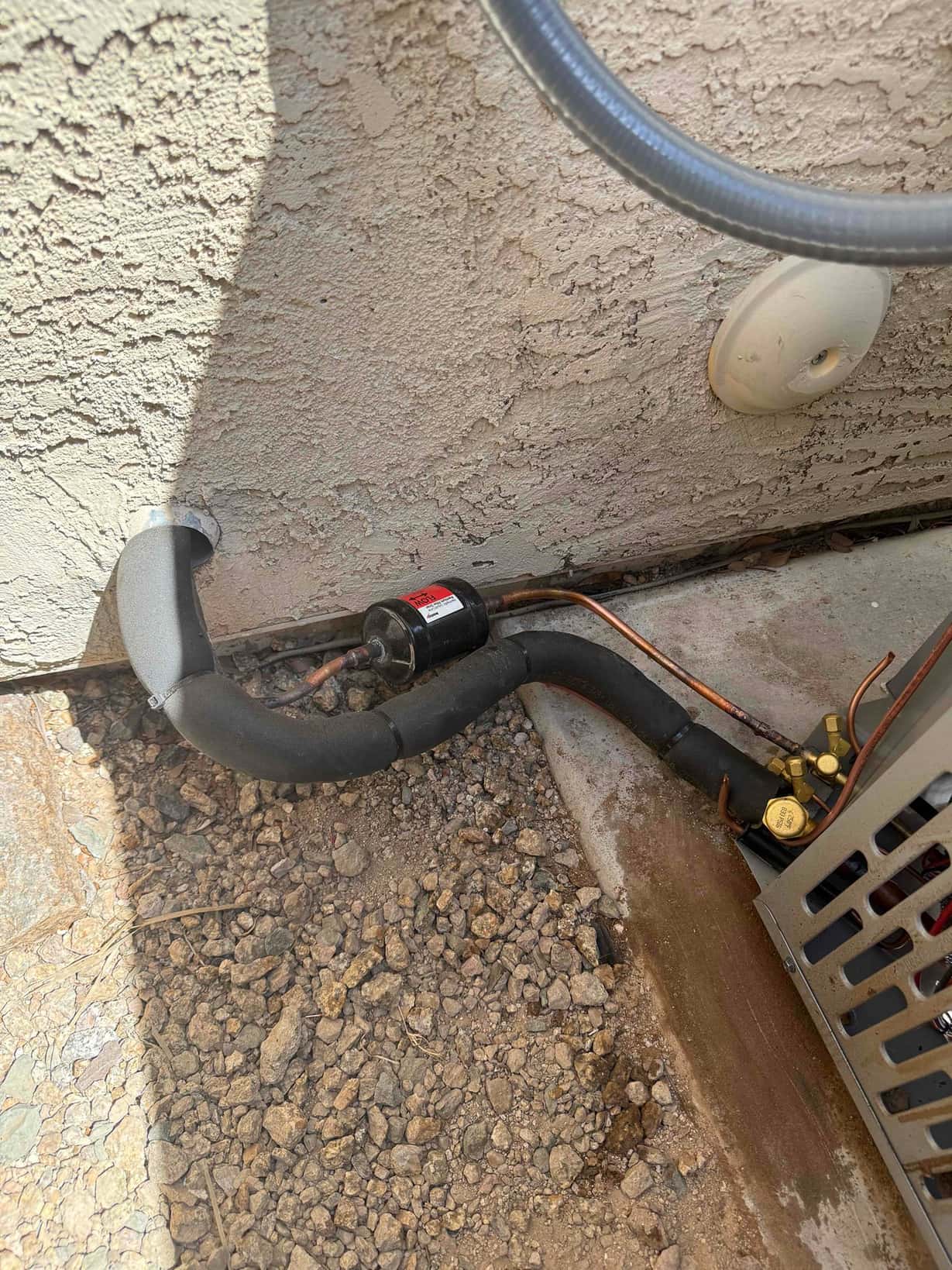 Insulated suction line and bare liquid line neatly routed to the outdoor condenser with service valves accessible at the unit.