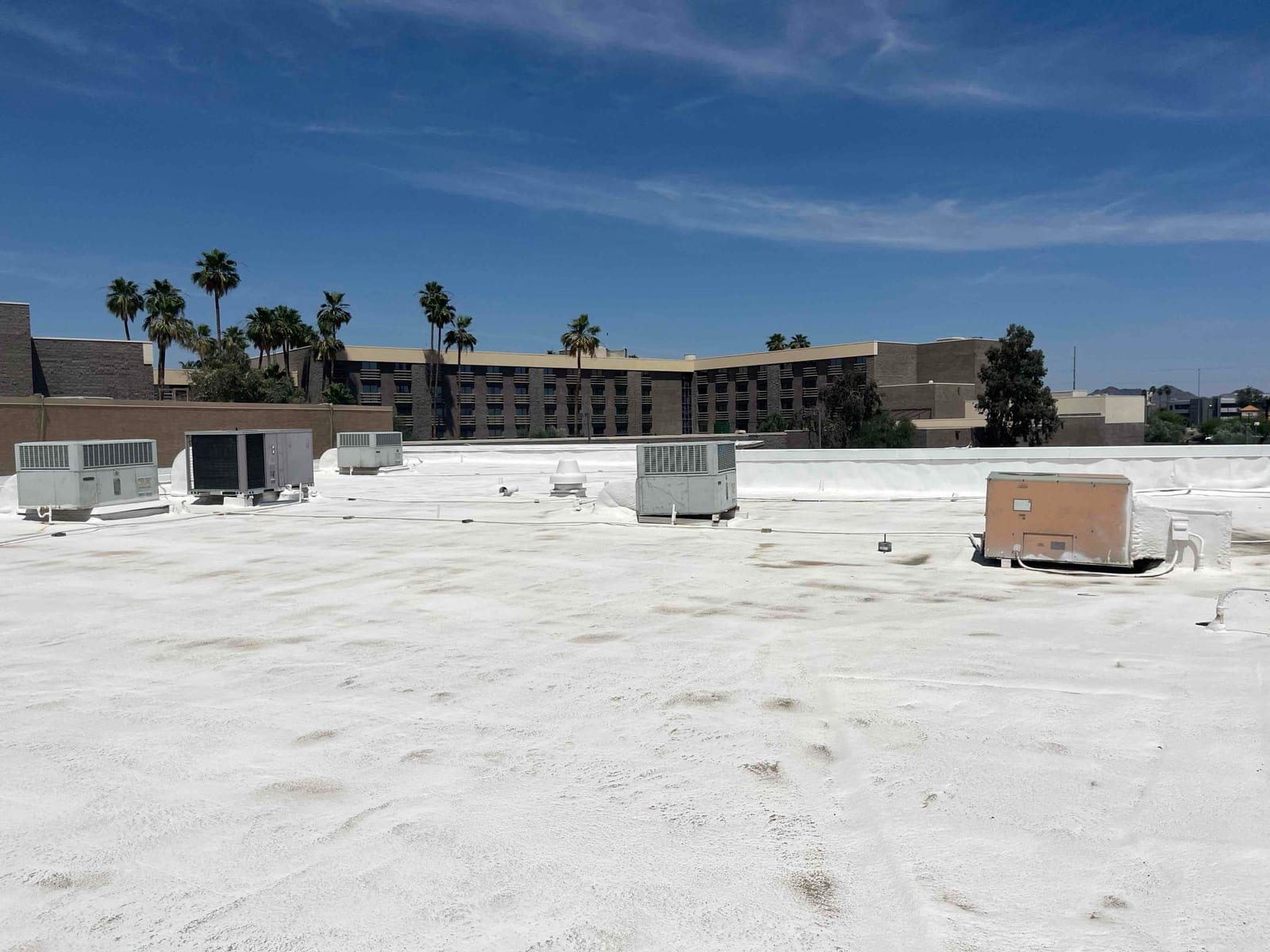 Multiple rooftop air conditioning units on a flat white roof under clear skies, showing equipment placement across the service area.