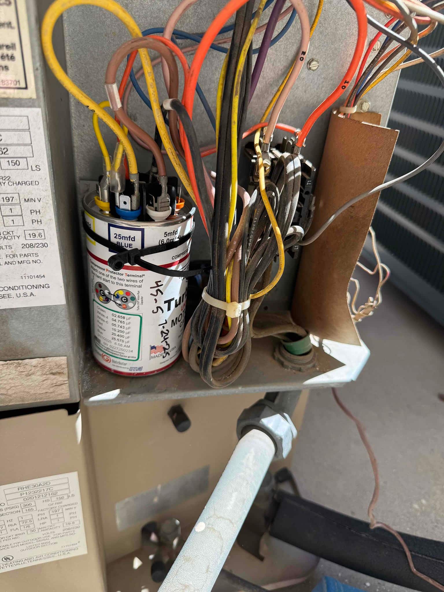 New dual-run capacitor installed with labeled terminals and connected wiring beside the contactor inside the outdoor condenser.