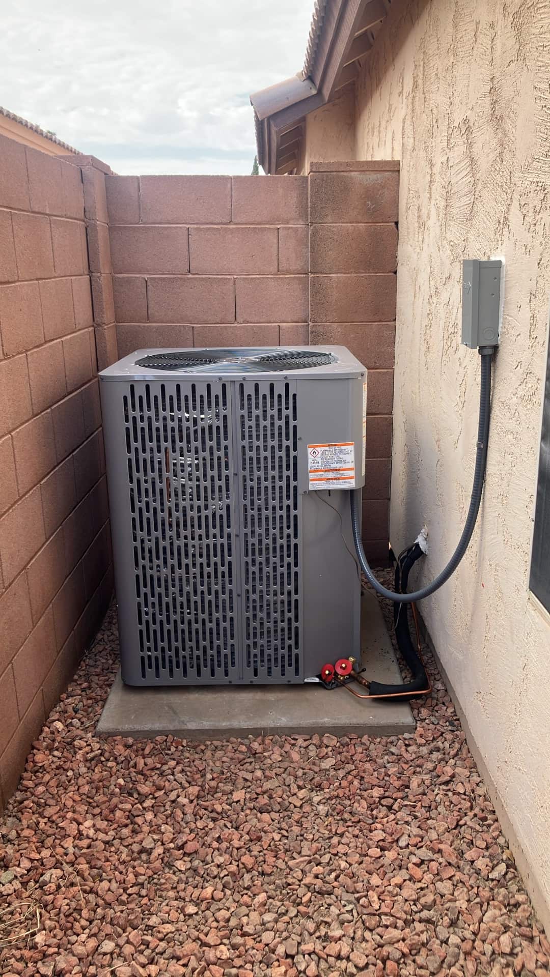 New heat pump condenser set on a level pad with insulated line set and outdoor disconnect installed.