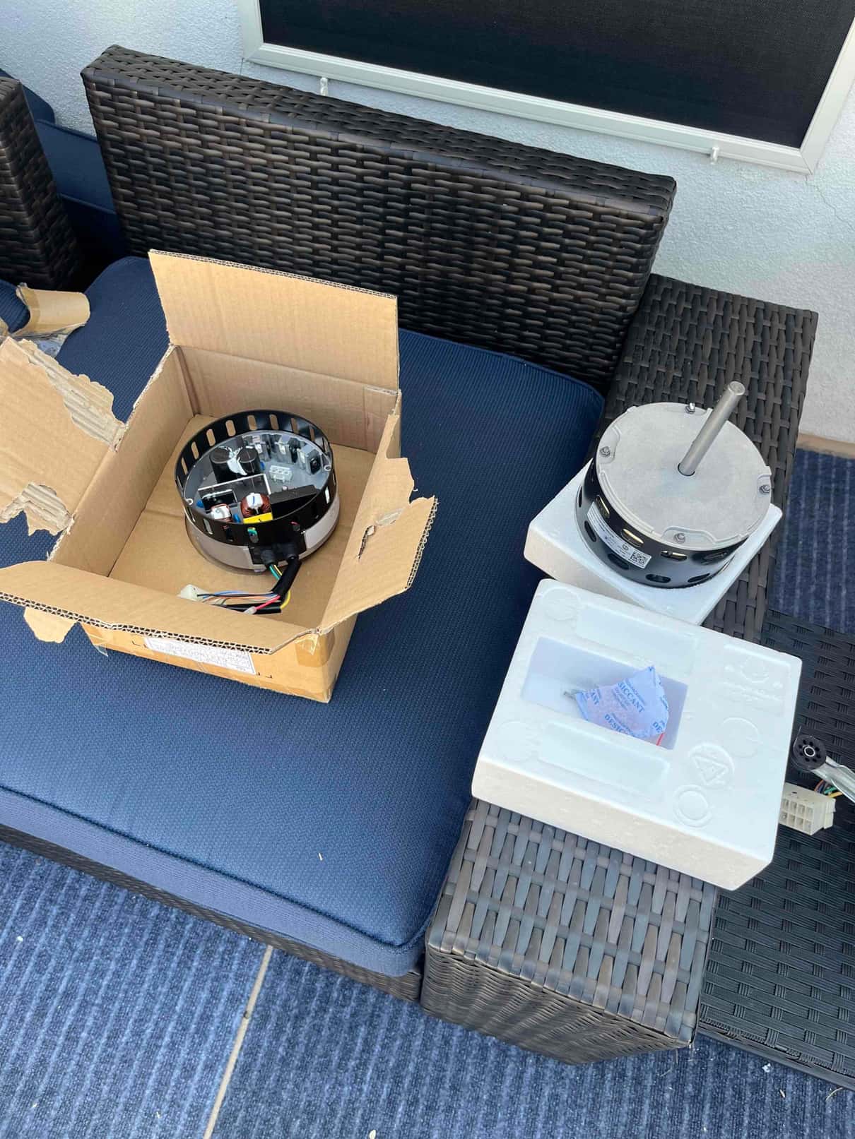 New indoor blower motor and housing sit on packaging foam and box on a bench, ready for installation.