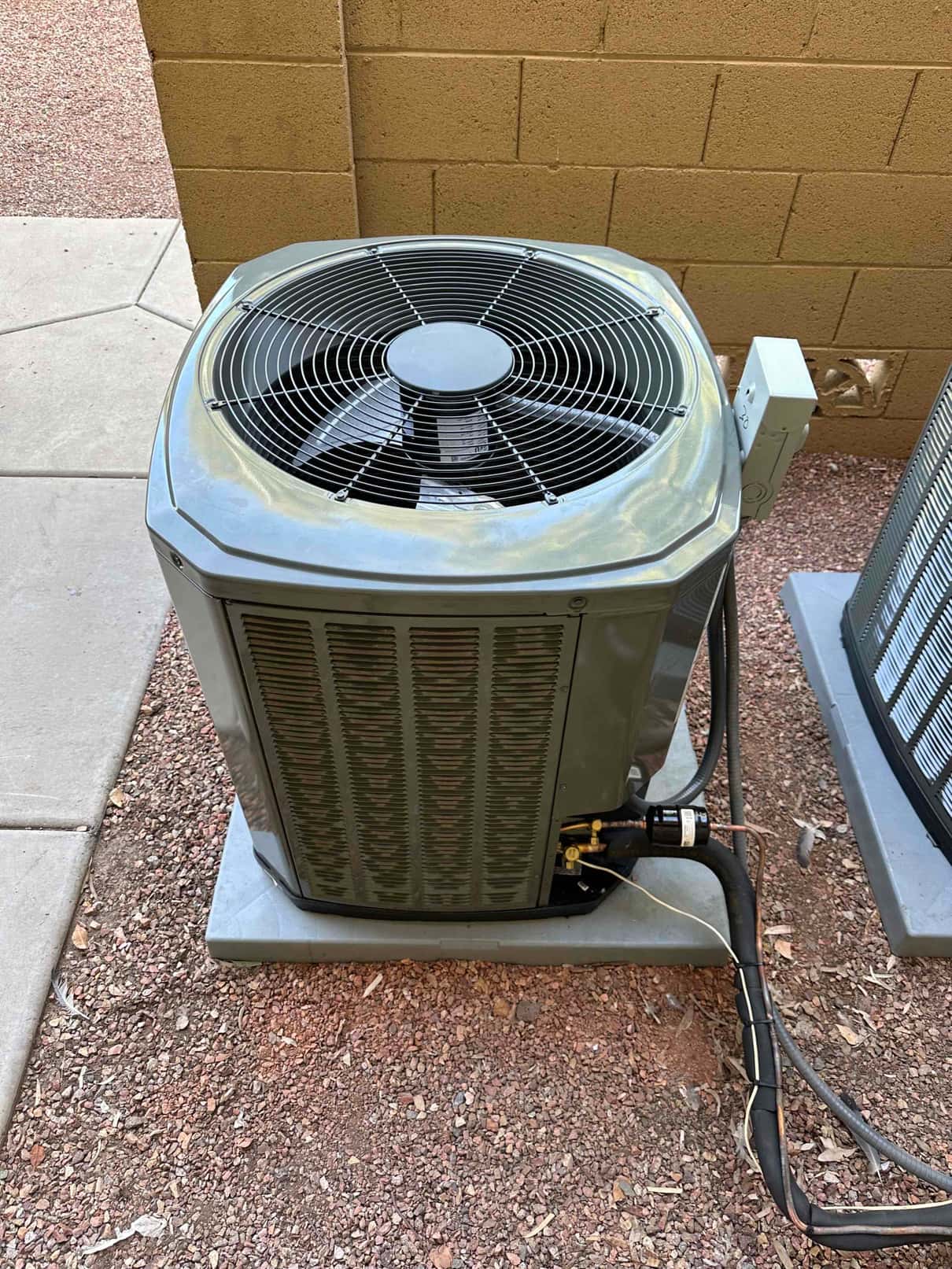 New outdoor heat pump condenser set on a level pad with insulated refrigerant lines and electrical disconnect mounted nearby.