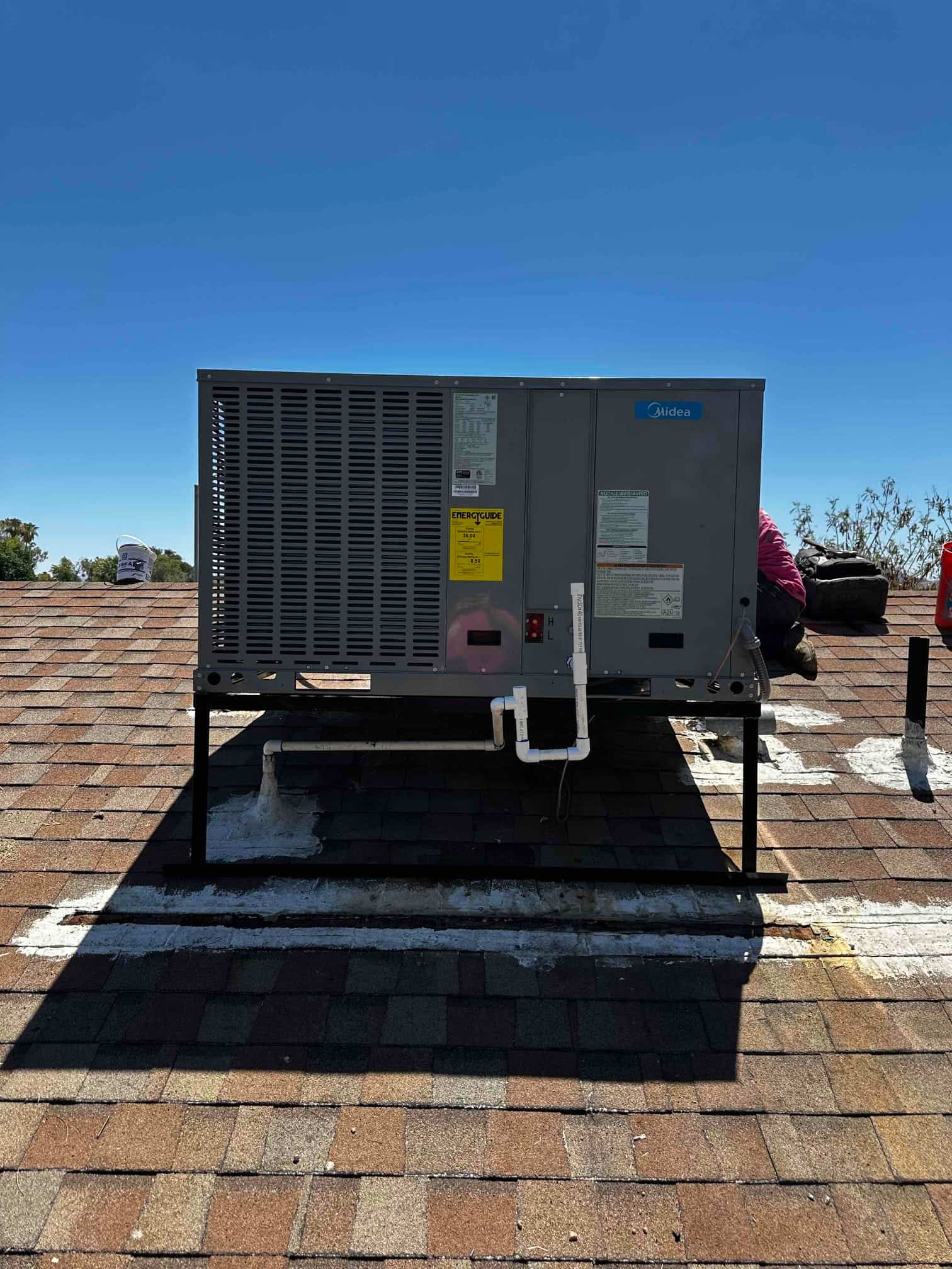 New rooftop package HVAC unit mounted on a metal stand with sealed roof penetrations and condensate drain piping connected.