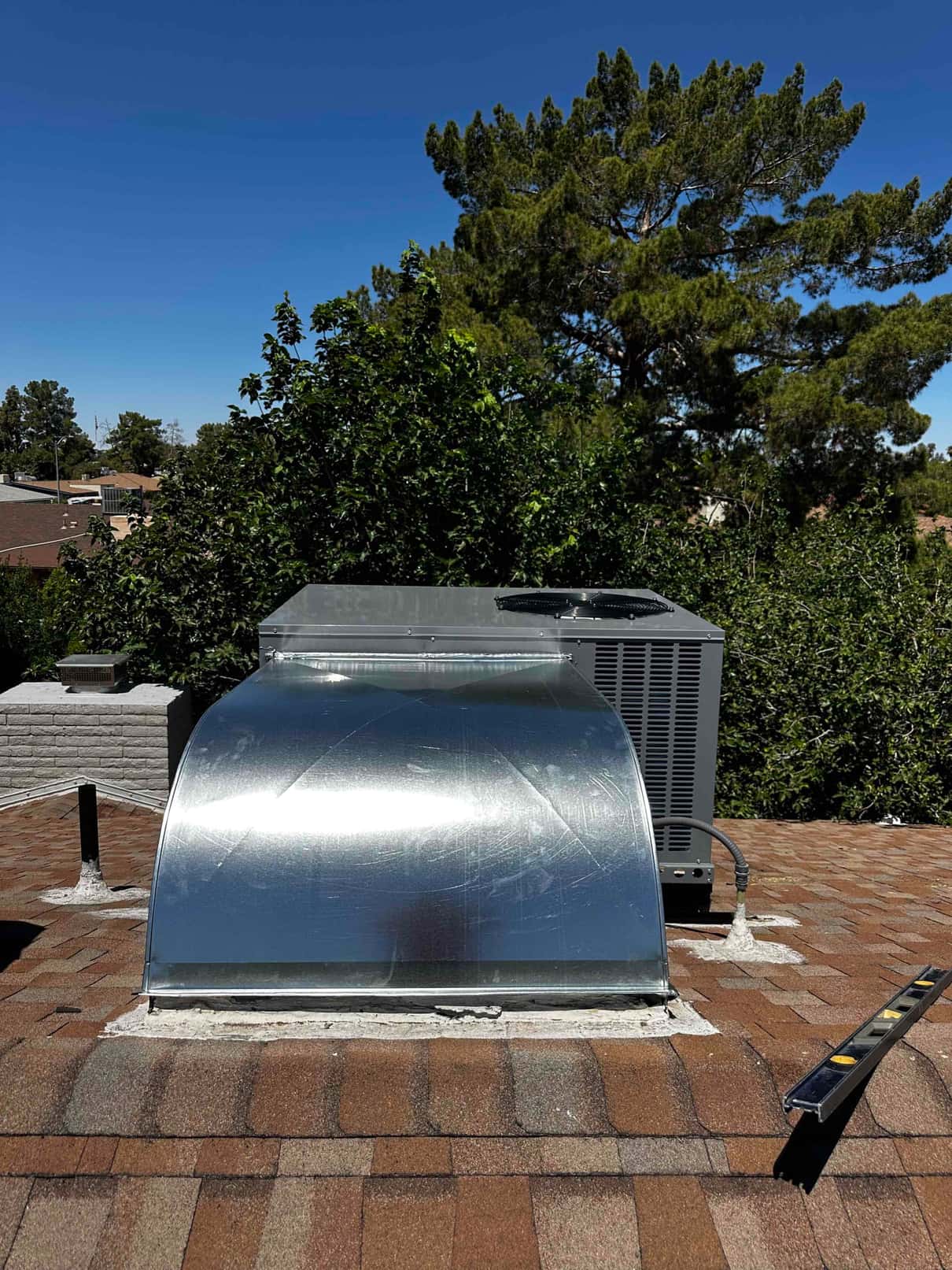 New rooftop package unit installed with sealed curb adapter and connected flexible conduit on a shingle roof.
