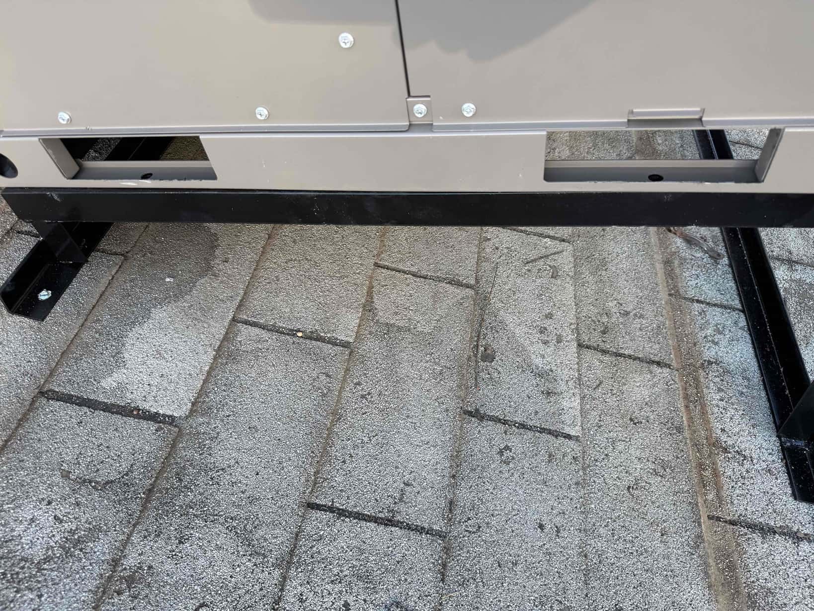 New rooftop package unit secured on a steel support frame, set level on the roof surface with fasteners visible.