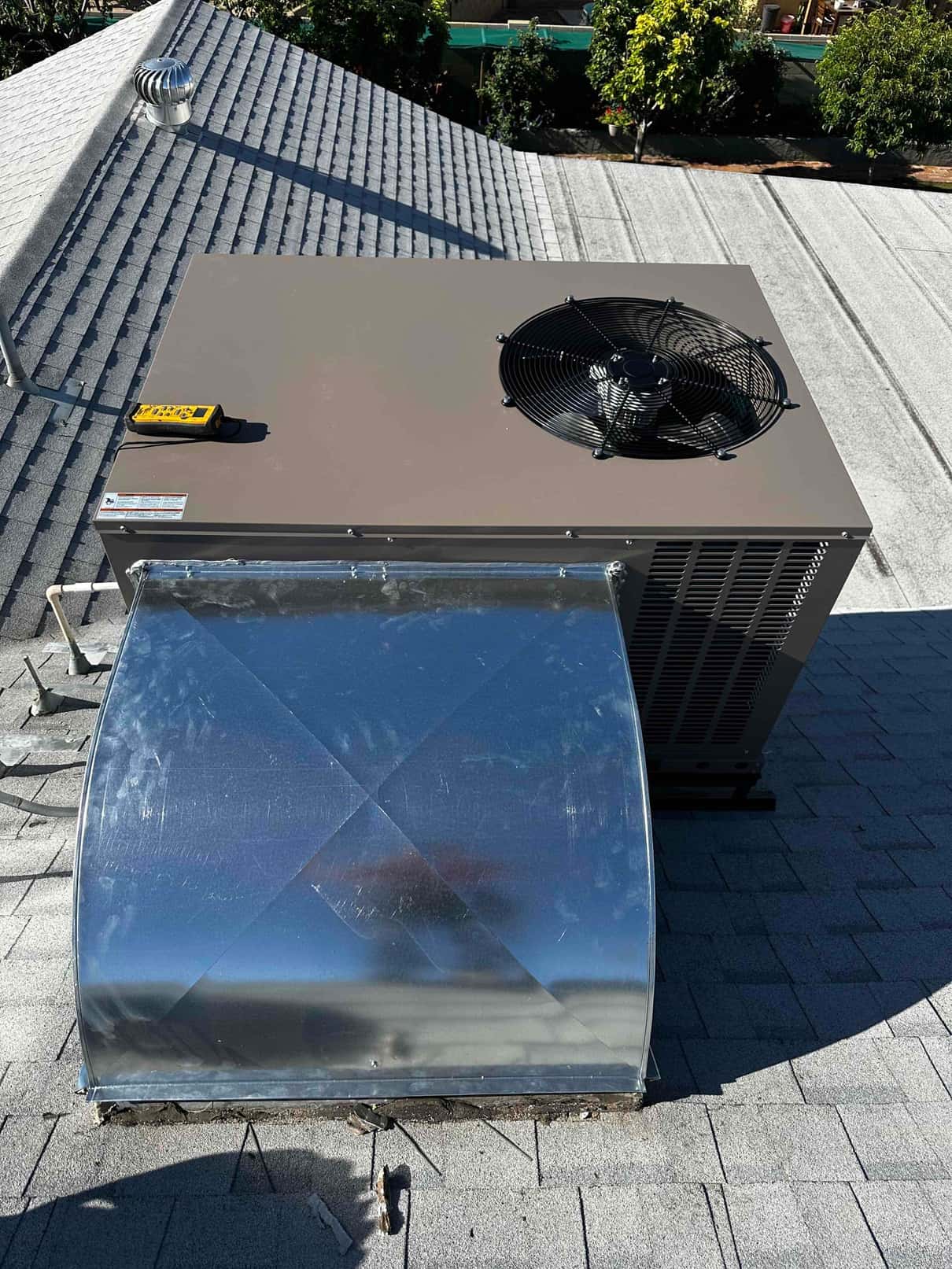 New rooftop package unit set on curb with connected sheet metal supply plenum and rooftop vent visible.