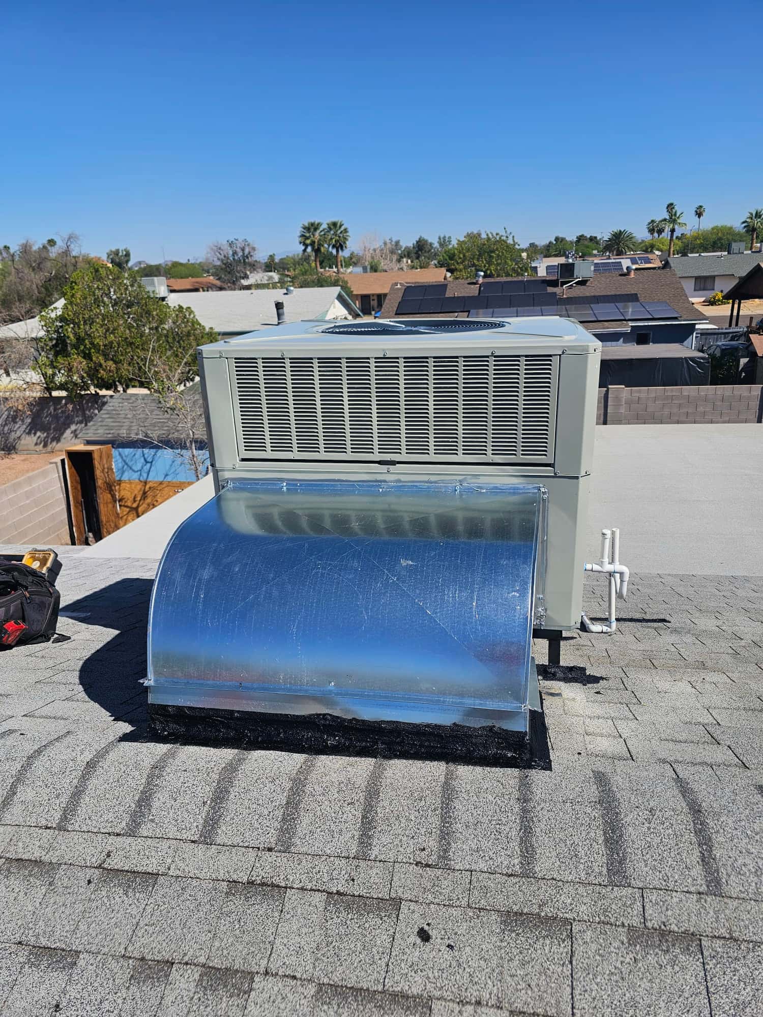 New rooftop package unit set on the roof with sealed curb adapter and connected condensate drain piping.