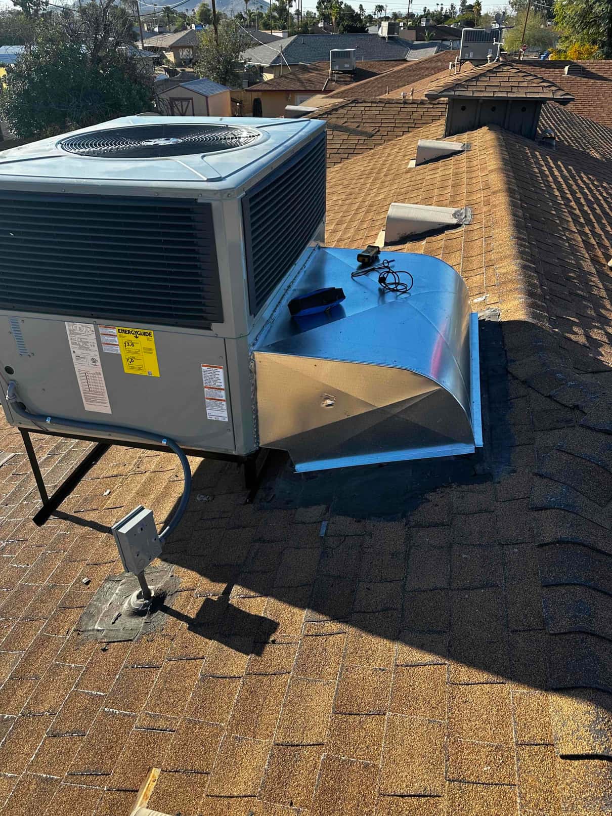 New rooftop packaged heat pump set on curb with sealed duct transition and weatherproof electrical disconnect installed nearby.