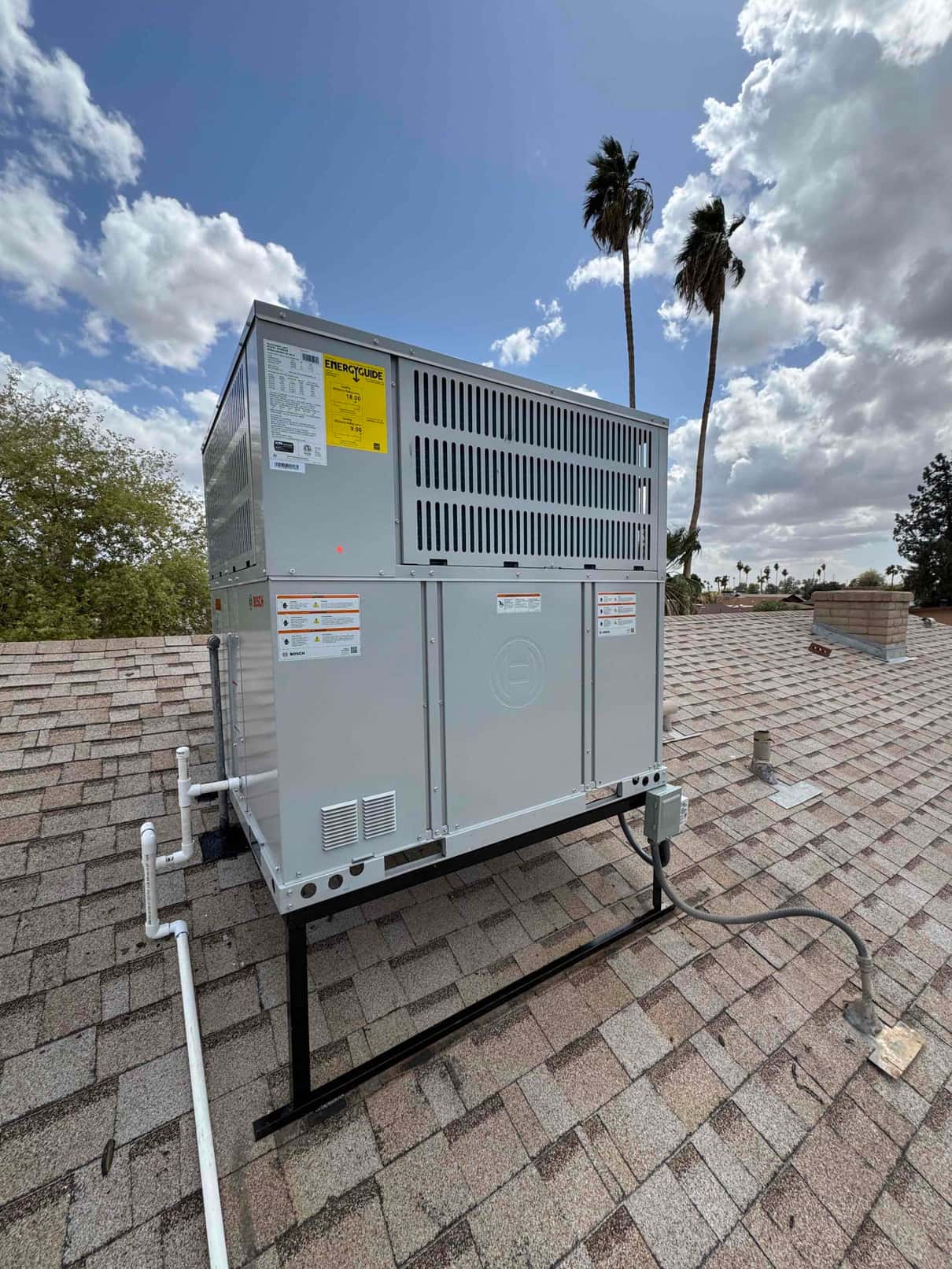 New rooftop packaged heat pump set on a metal curb with condensate drain piping and weatherproof electrical disconnect connected.