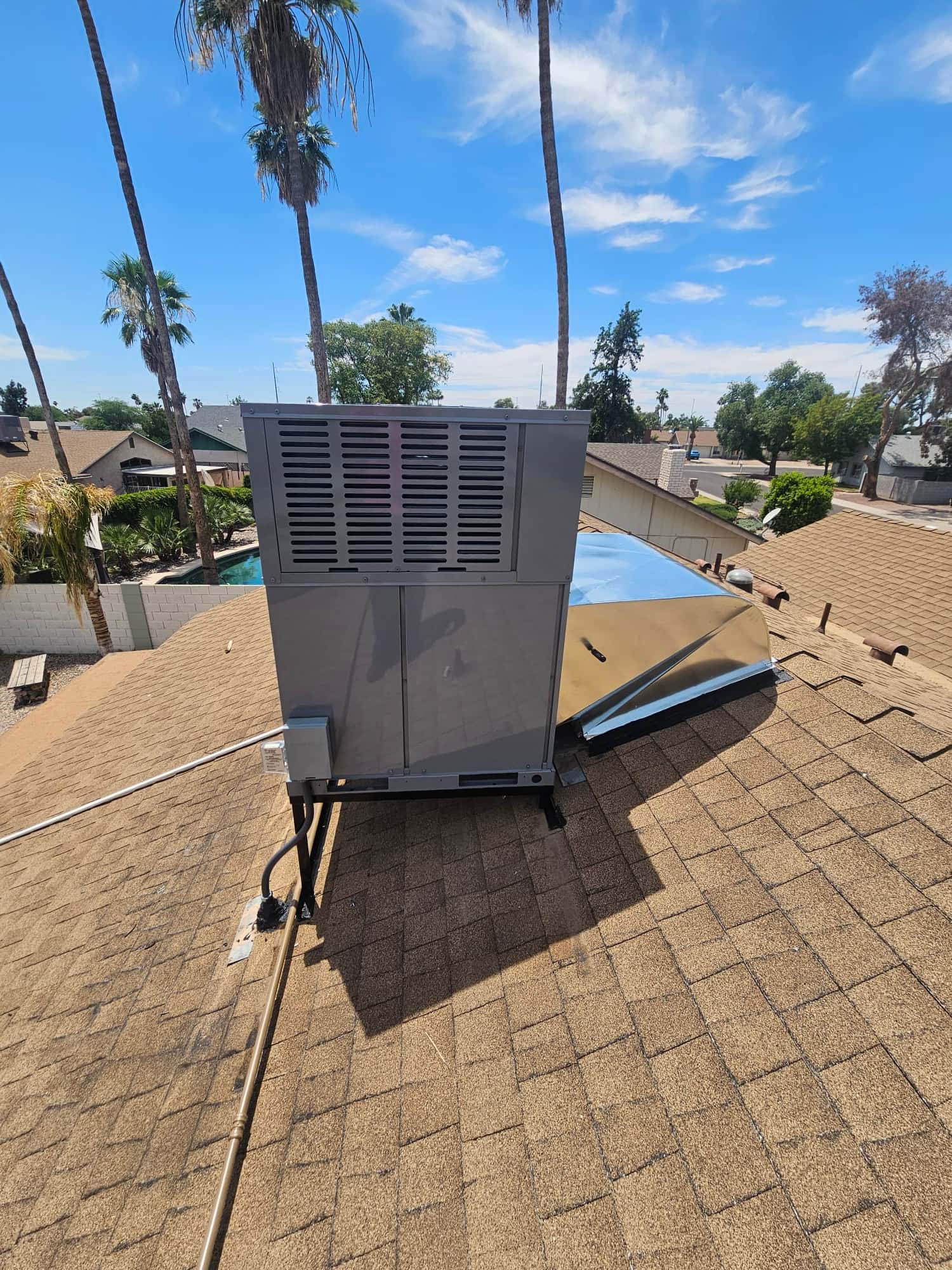 New rooftop packaged HVAC unit set on curb with sealed roof penetration, electrical disconnect, and duct transition in place.