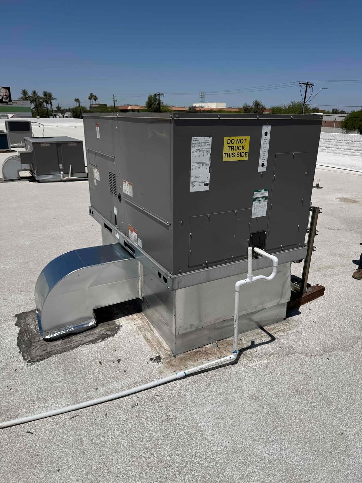 New rooftop packaged unit installed on curb with sealed duct transition and routed condensate drain line visible.